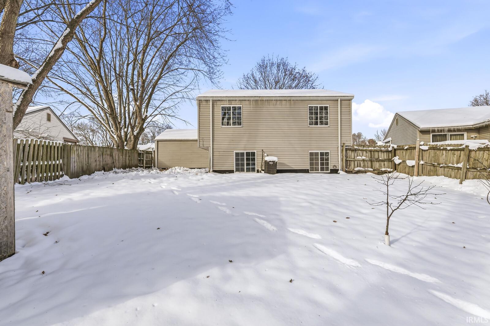 Snow covered house featuring a fenced backyard