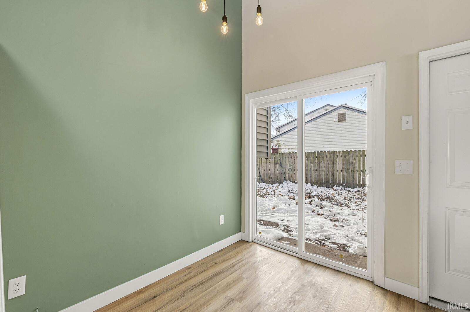 Empty room with light wood-style flooring and a towering ceiling