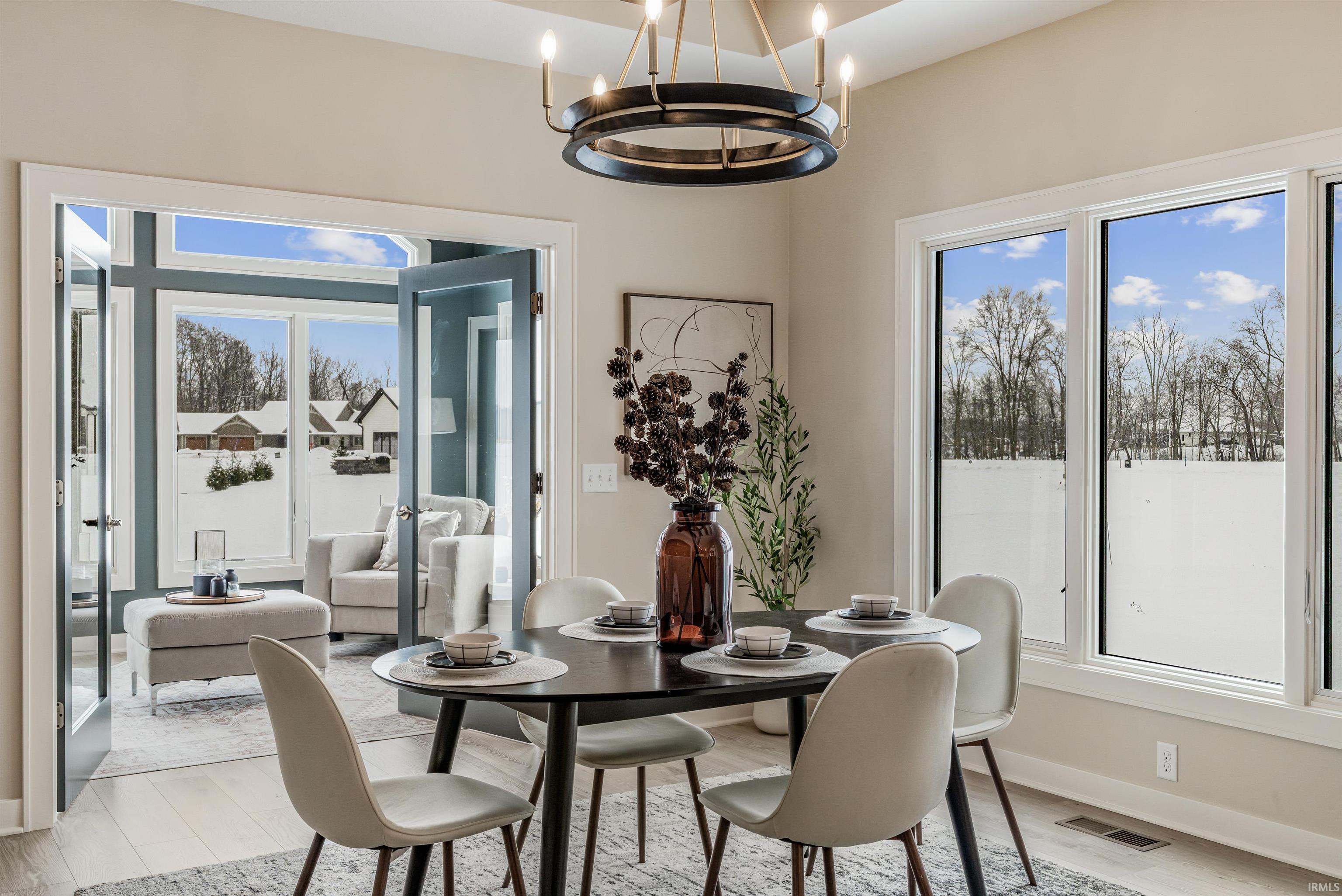 Dining area with light wood-style flooring, plenty of natural light, and a chandelier