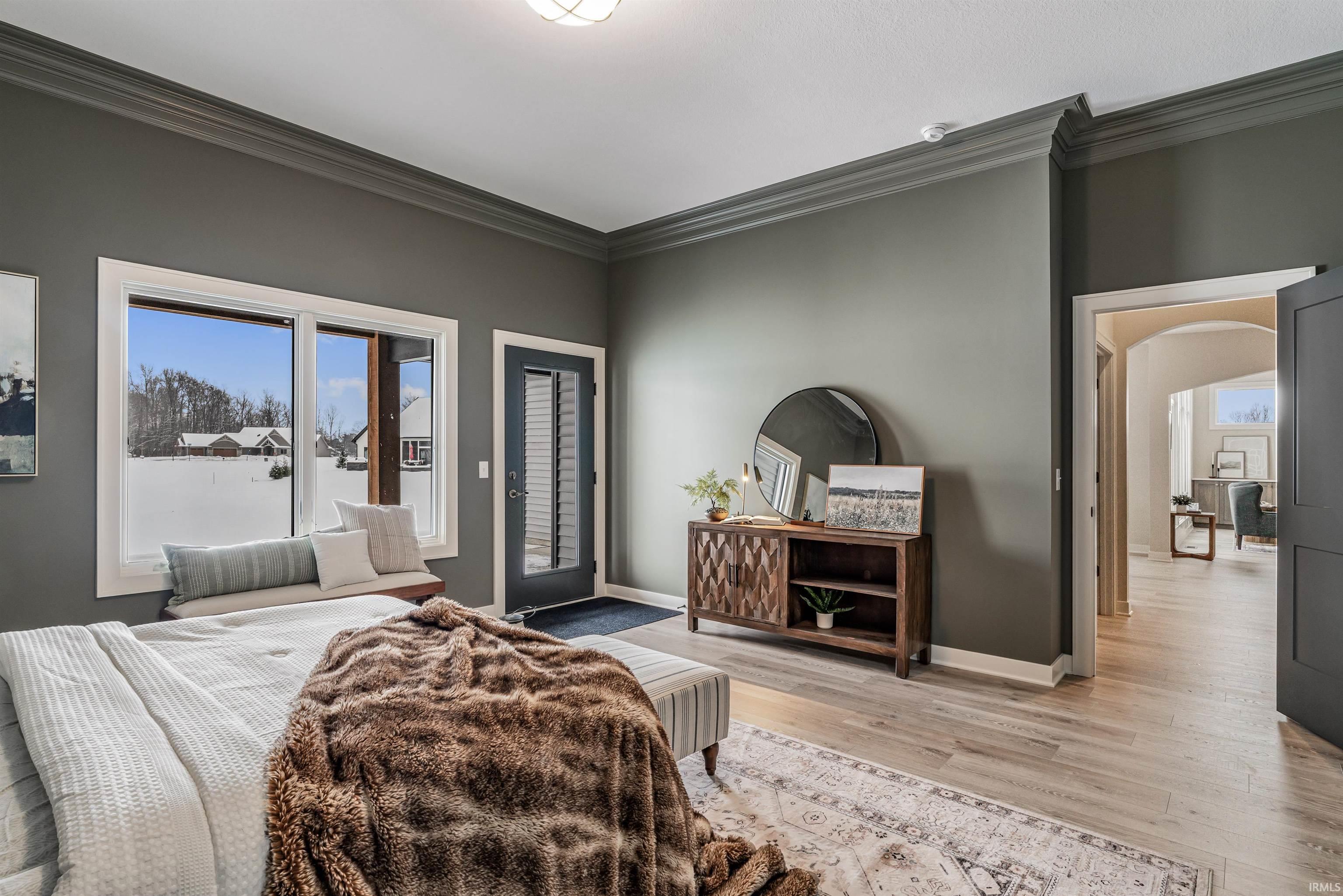 Bedroom with crown molding, arched walkways, access to exterior, and light wood-style flooring