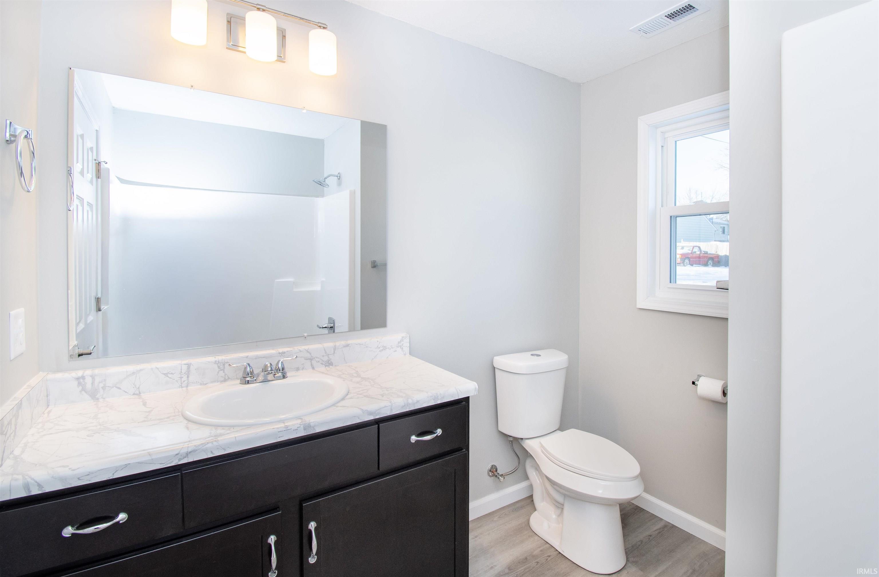 Full bathroom featuring vanity, light wood finished floors, and a shower