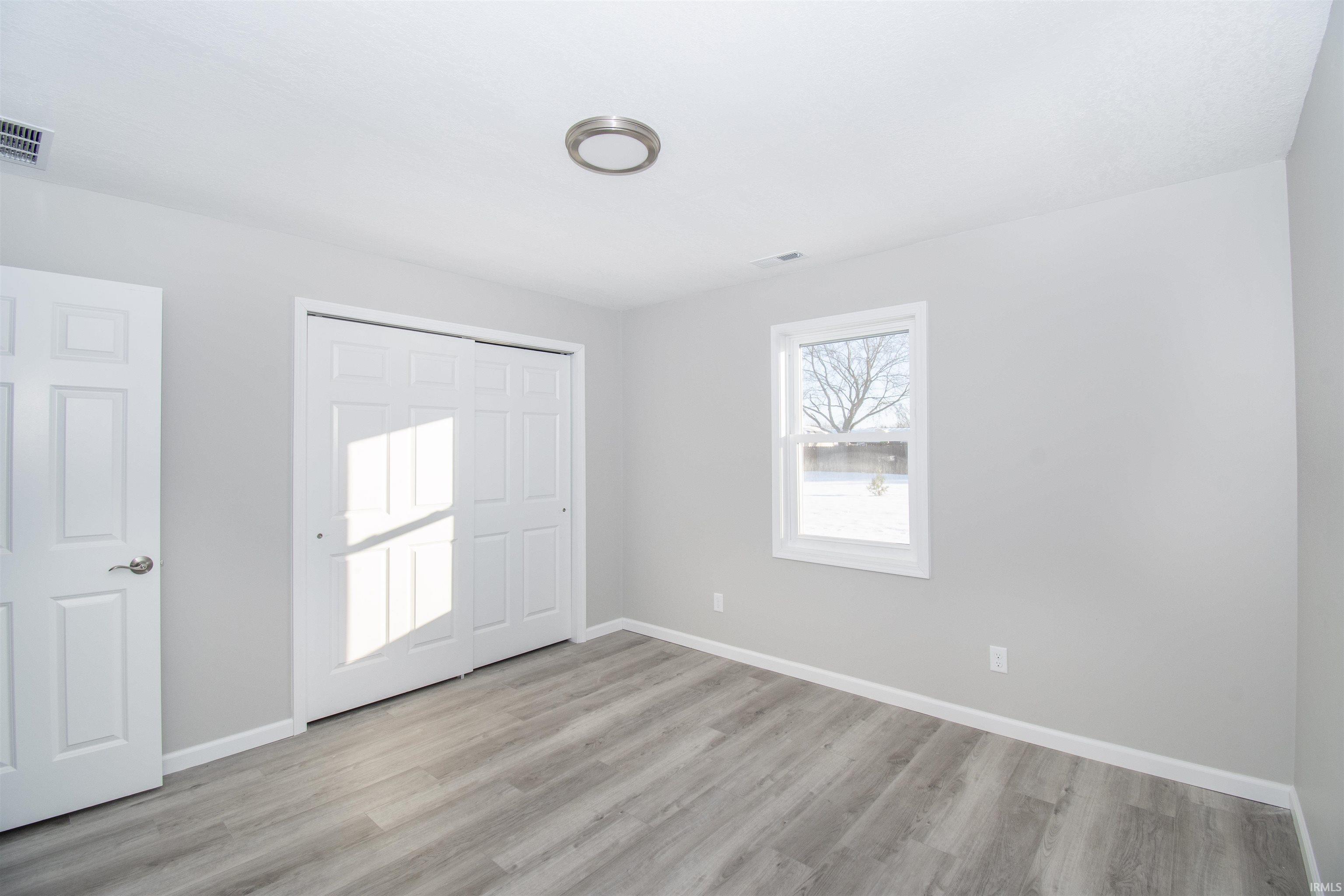 Unfurnished bedroom with light wood-style floors and a closet