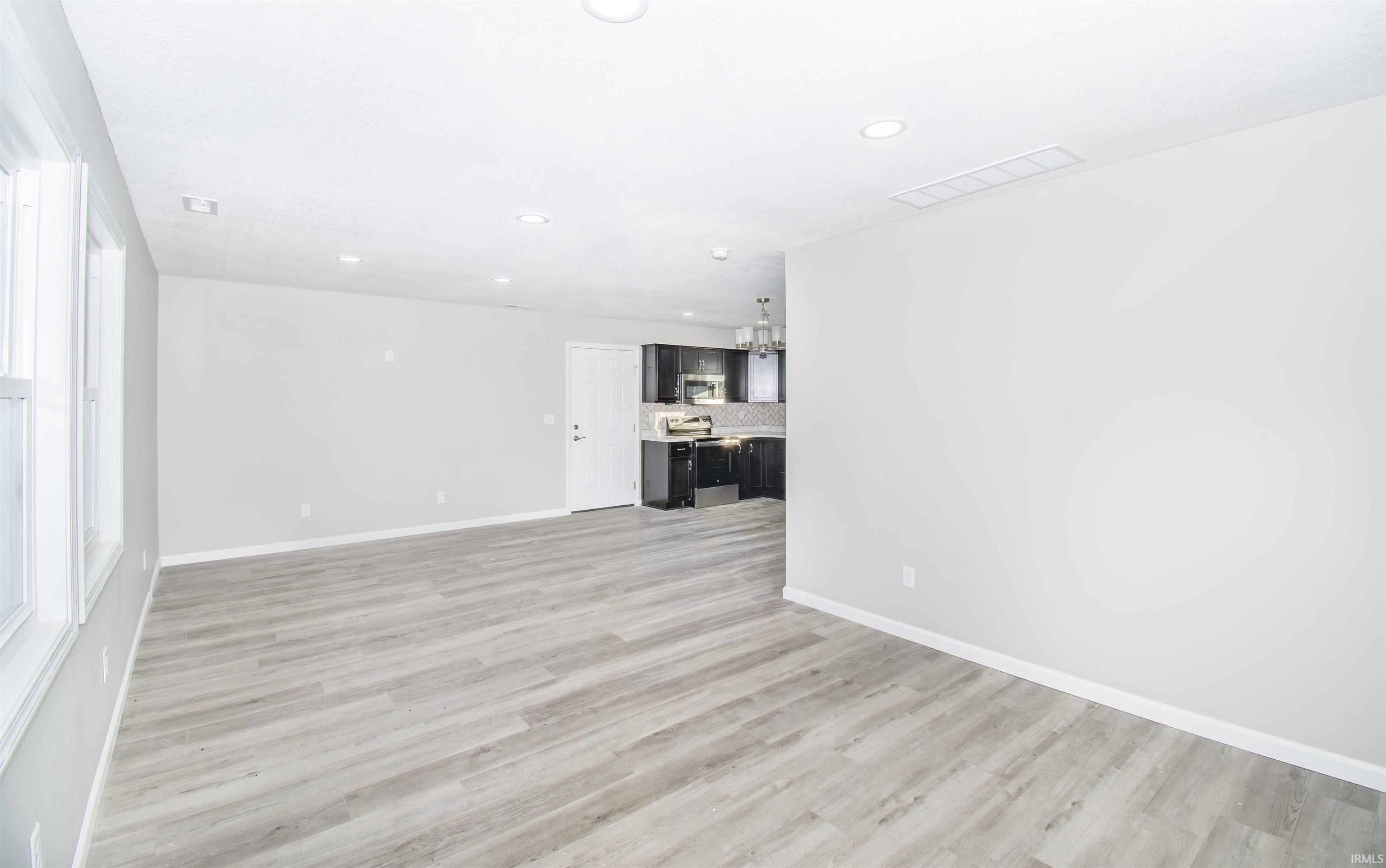 Unfurnished living room featuring recessed lighting, light wood finished floors, and a chandelier