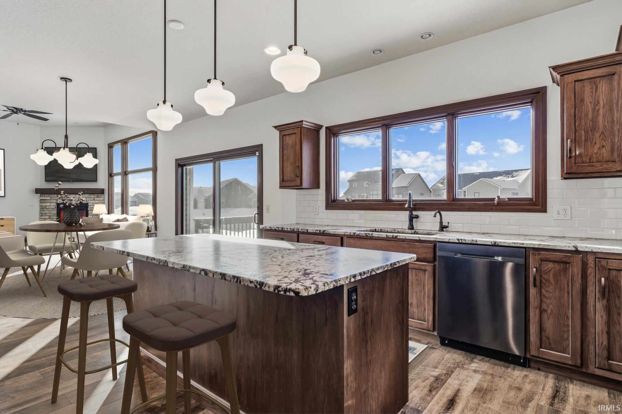 Kitchen with decorative backsplash, a kitchen island, hanging light fixtures, dishwasher, and a breakfast bar area