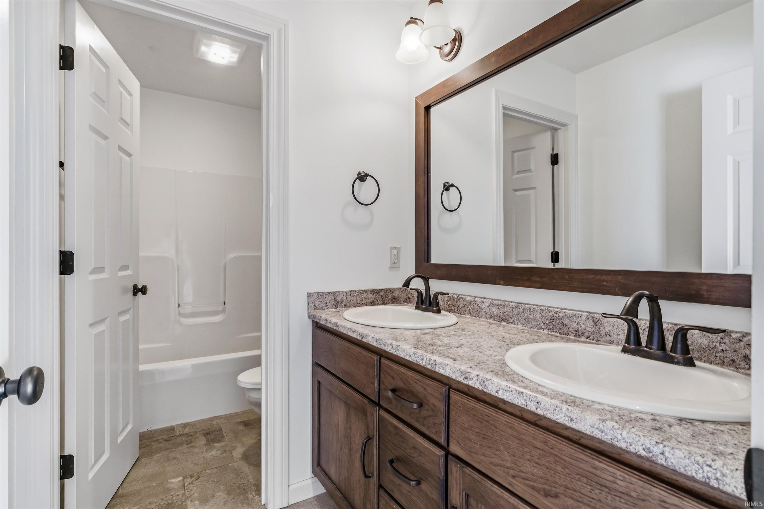 Full bathroom with double vanity and shower / bathtub combination