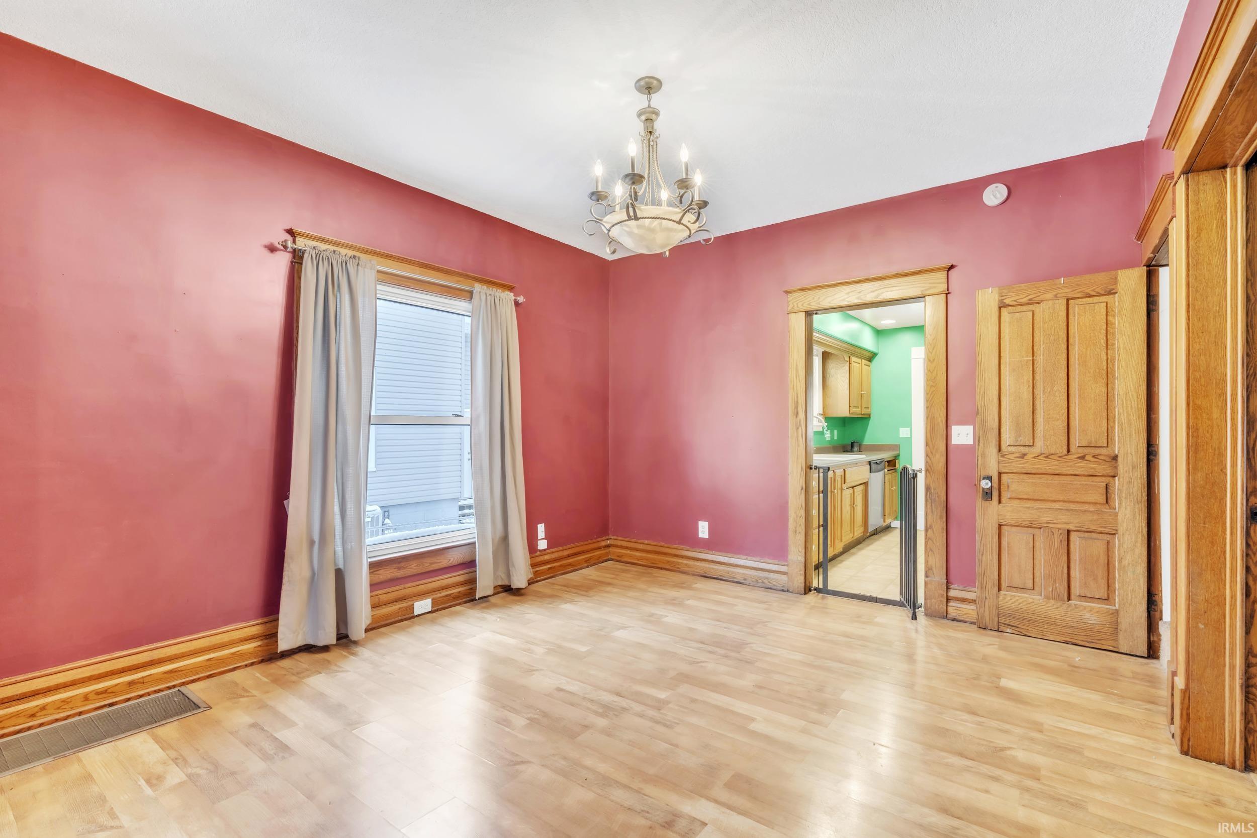 Spare room with a chandelier and light wood-type flooring