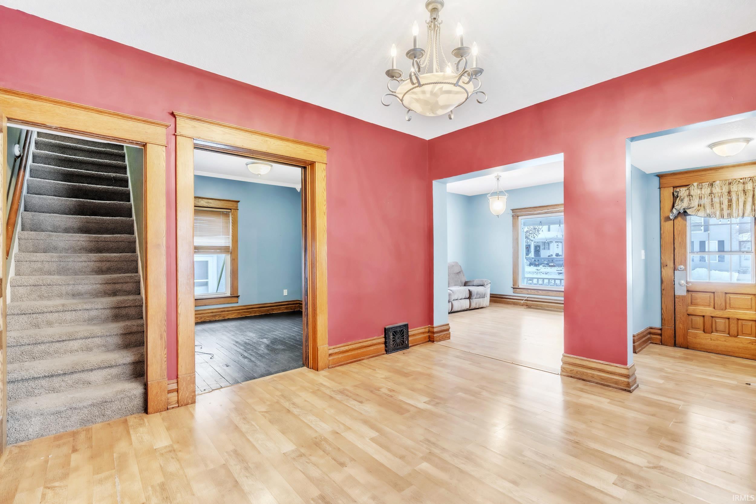 Unfurnished dining area with wood finished floors, a chandelier, stairs, and a baseboard heating unit