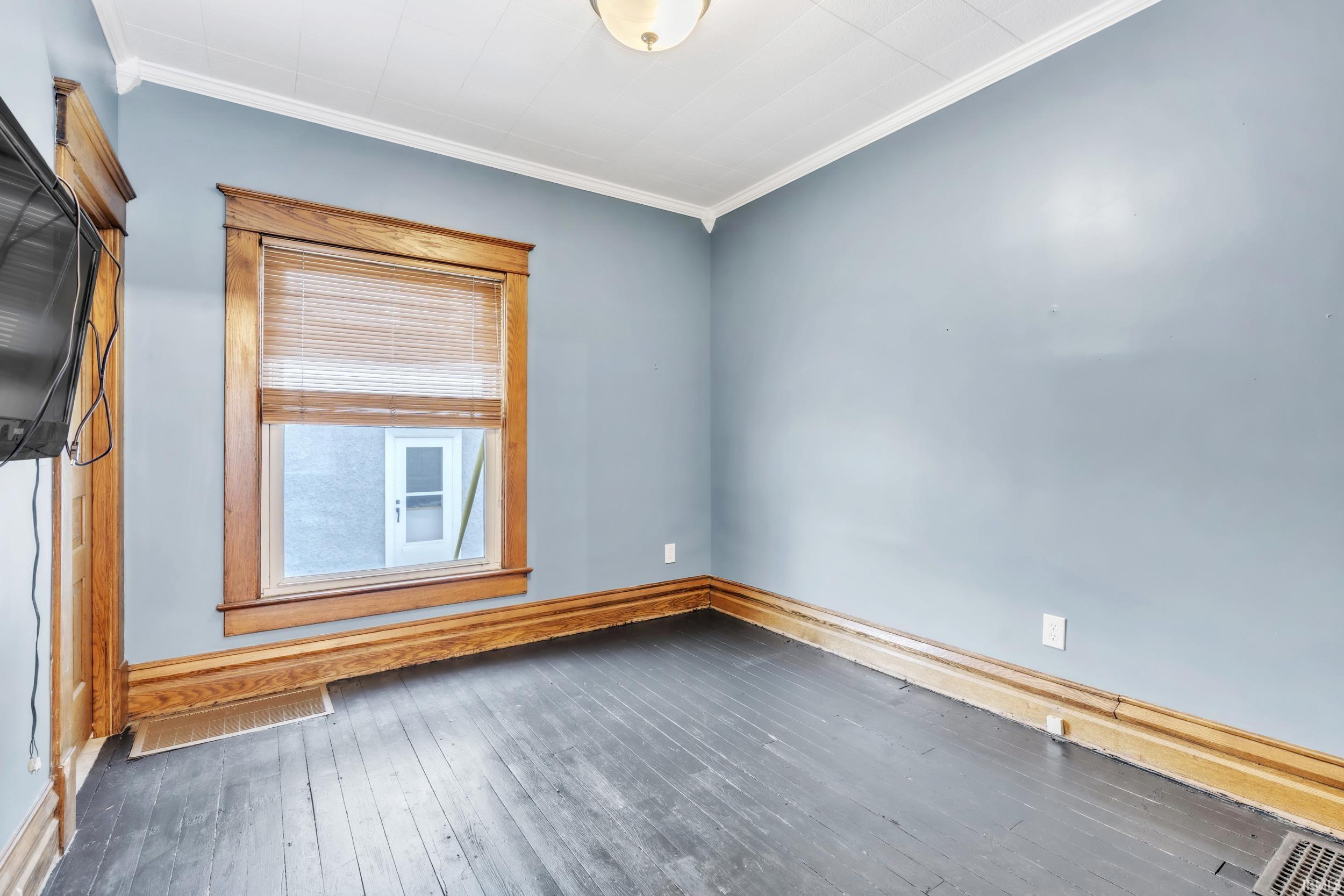 Spare room with wood-type flooring and crown molding