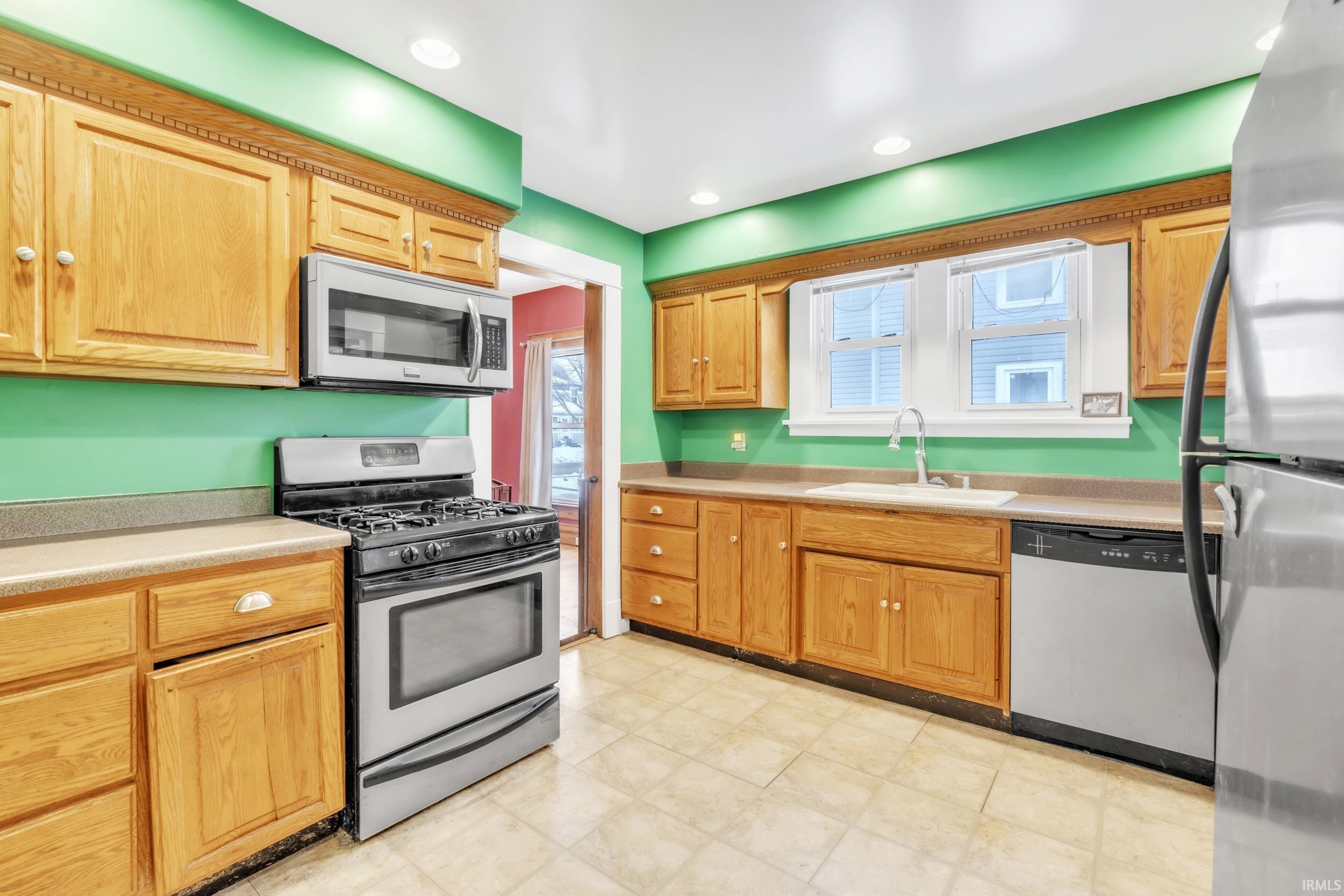 Kitchen with appliances with stainless steel finishes, light countertops, light floors, and recessed lighting