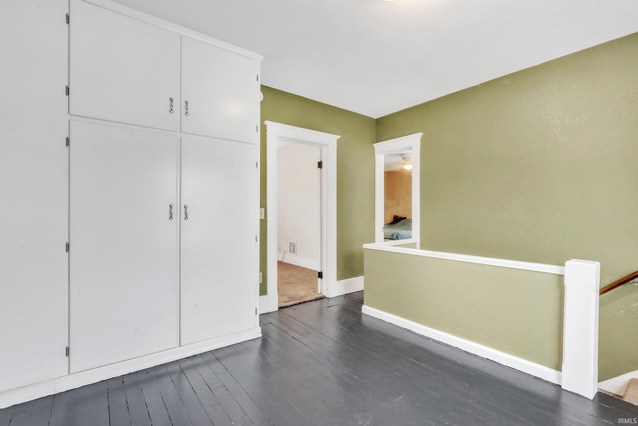 Unfurnished bedroom featuring dark wood-style floors and a closet