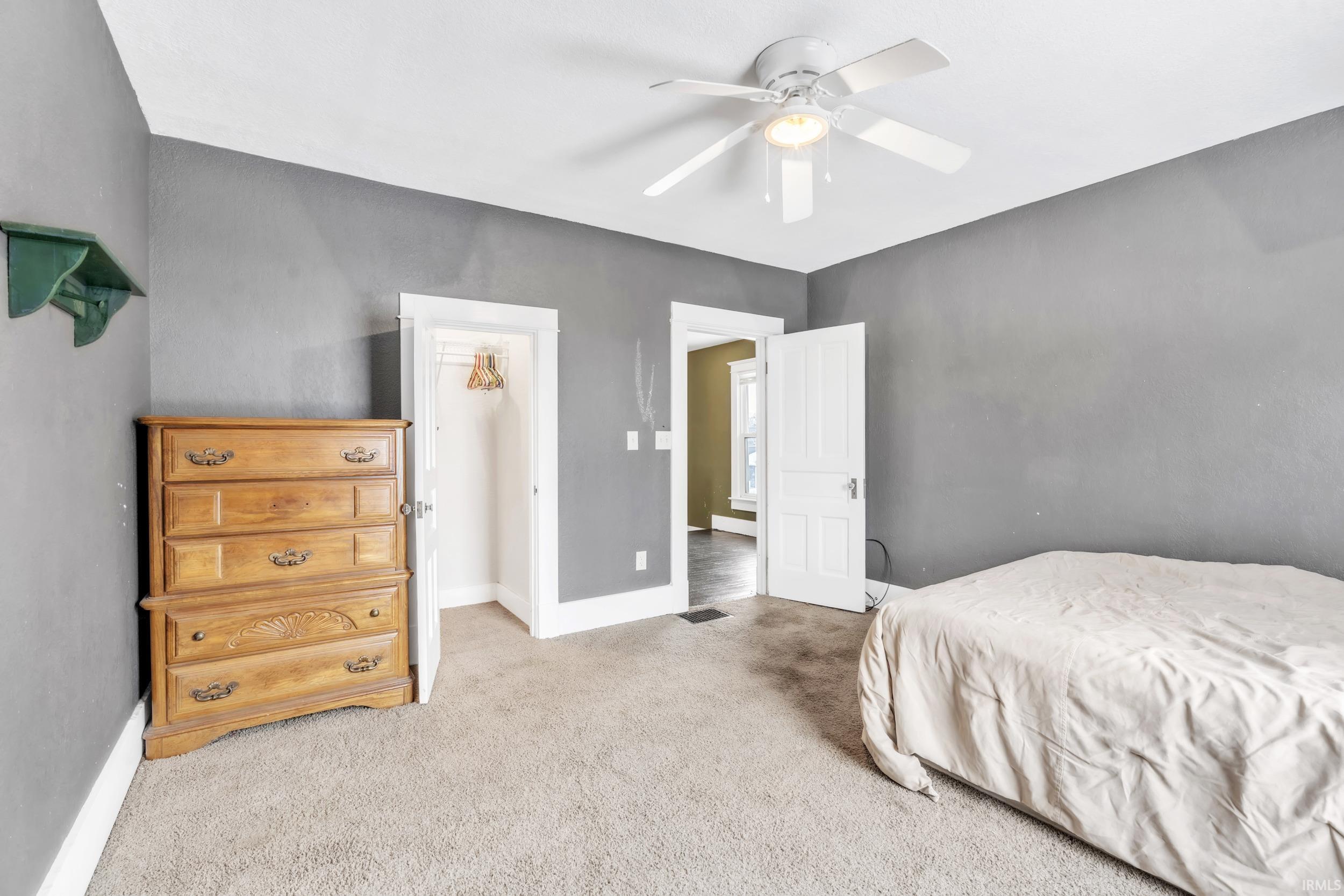 Carpeted bedroom featuring a ceiling fan and a spacious closet