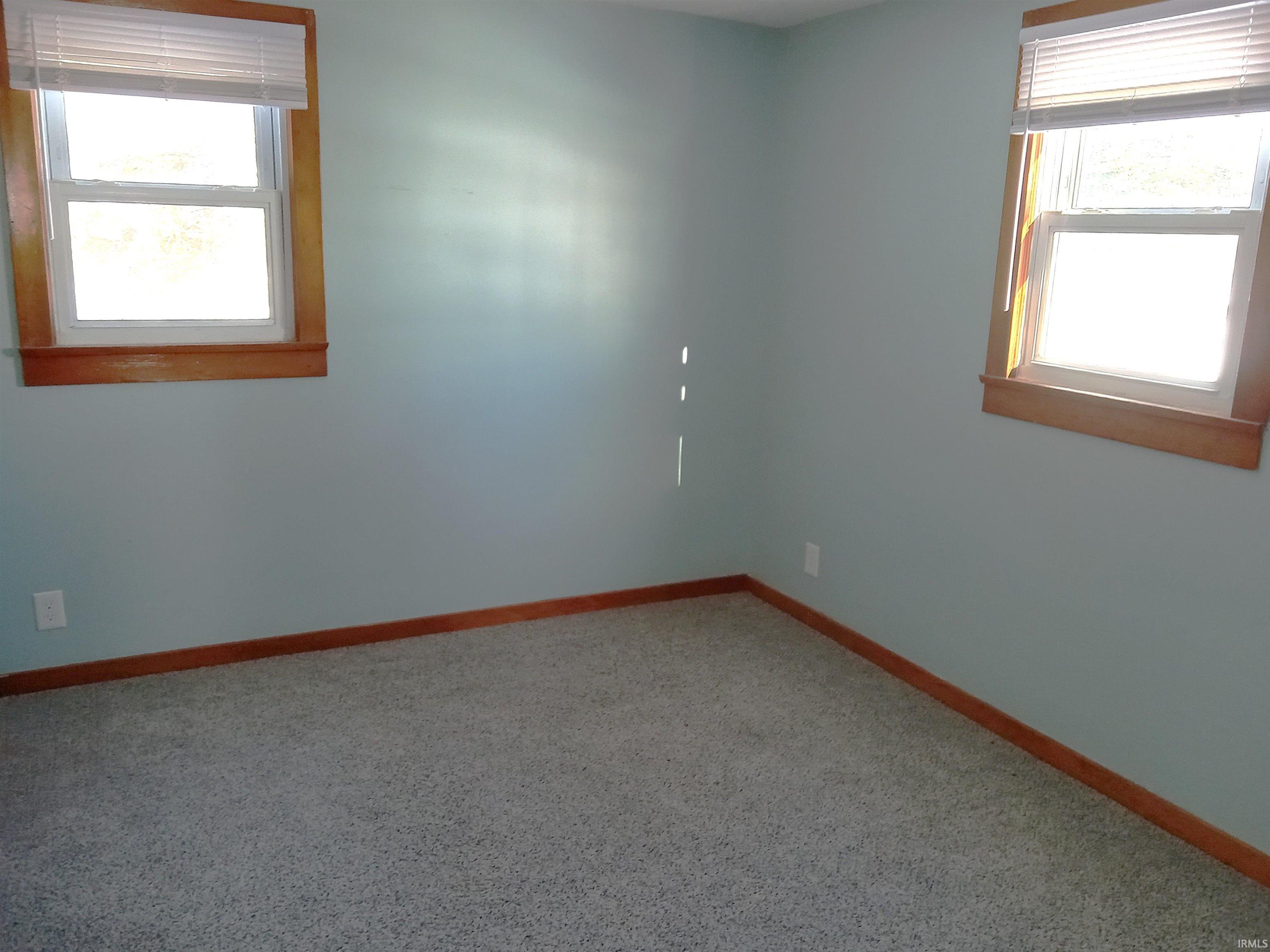 Unfurnished room with baseboards and light colored carpet