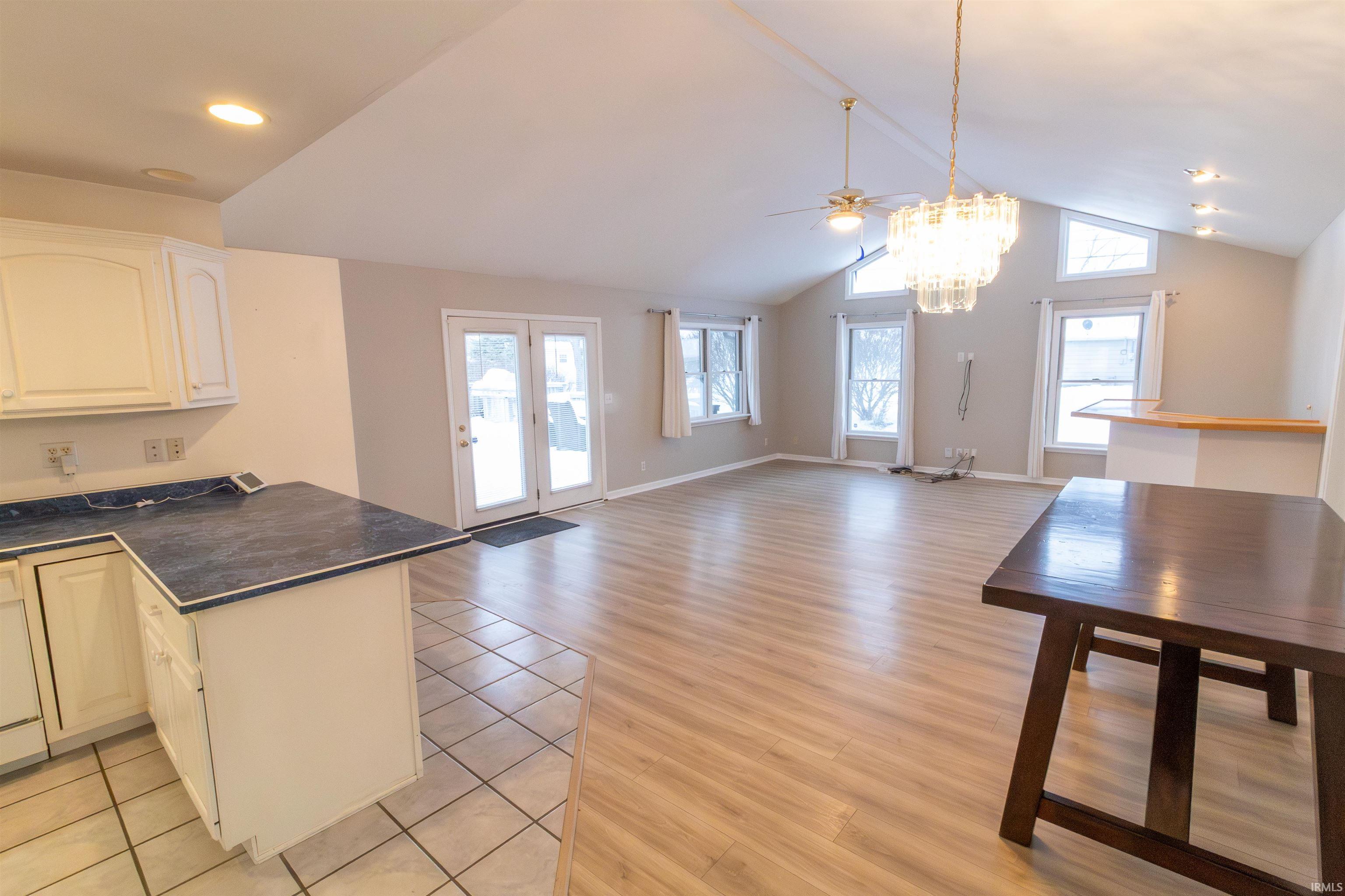 Kitchen featuring dark countertops, a peninsula, open floor plan, decorative light fixtures, and ceiling fan