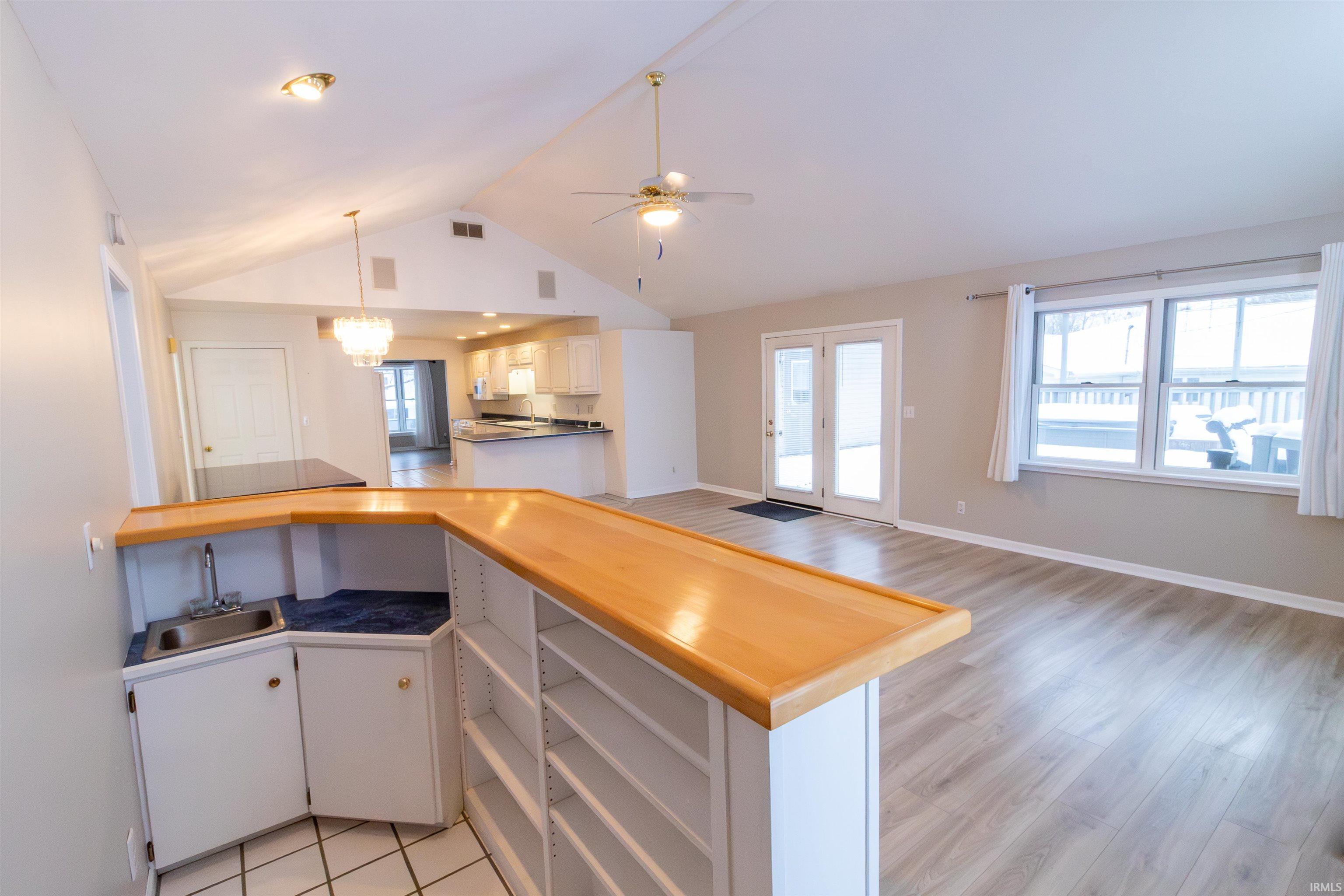 Kitchen with white cabinetry, lofted ceiling, a peninsula, hanging light fixtures, and a ceiling fan