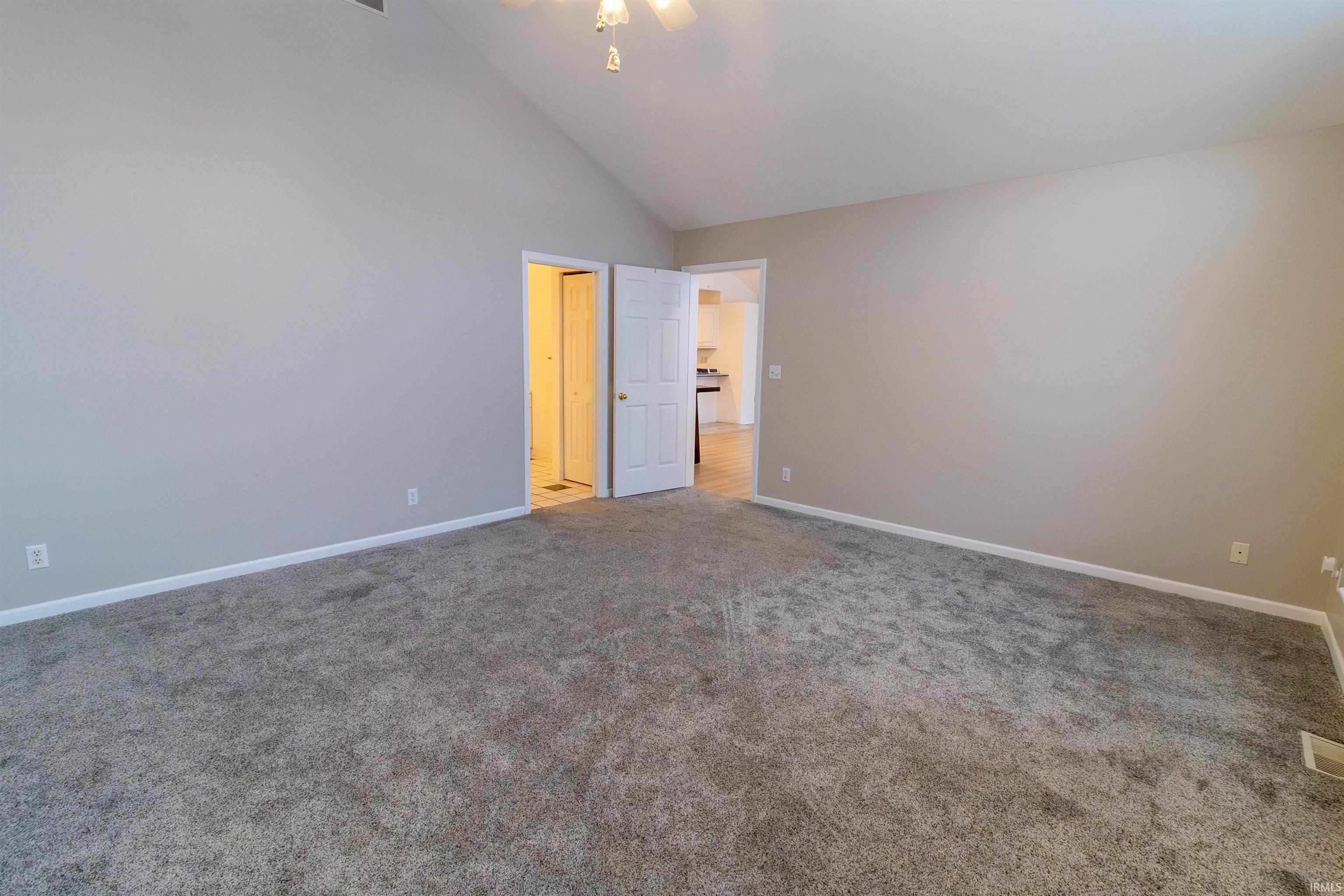 Unfurnished bedroom with high vaulted ceiling, carpet floors, and ceiling fan