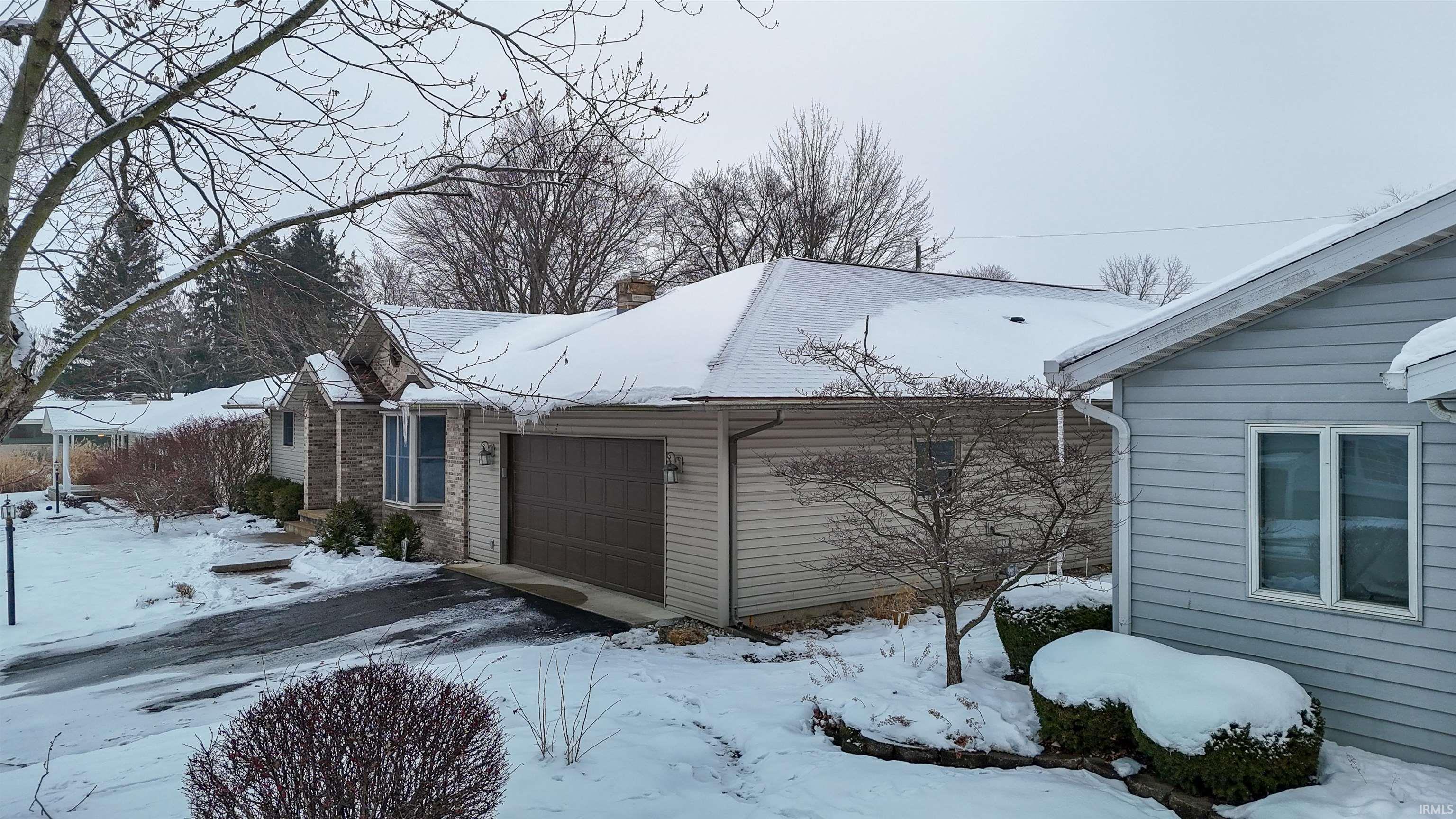 View of snowy exterior with a chimney and an attached garage