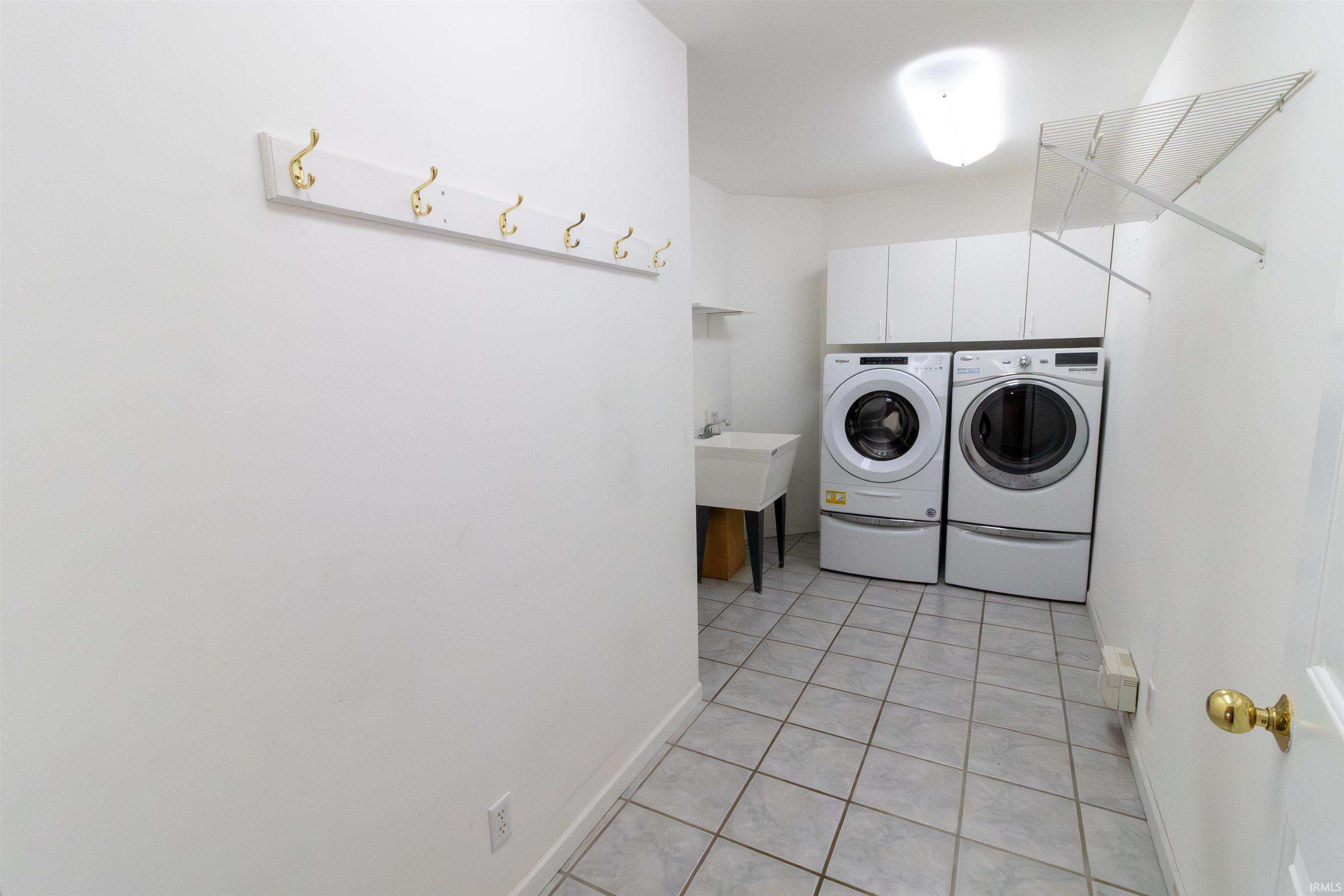 Laundry room with light tile patterned floors and separate washer and dryer