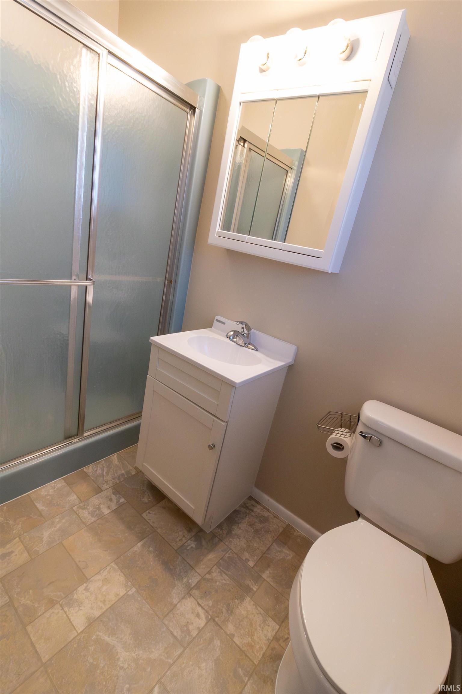 Bathroom with a stall shower, stone finish flooring, and vanity