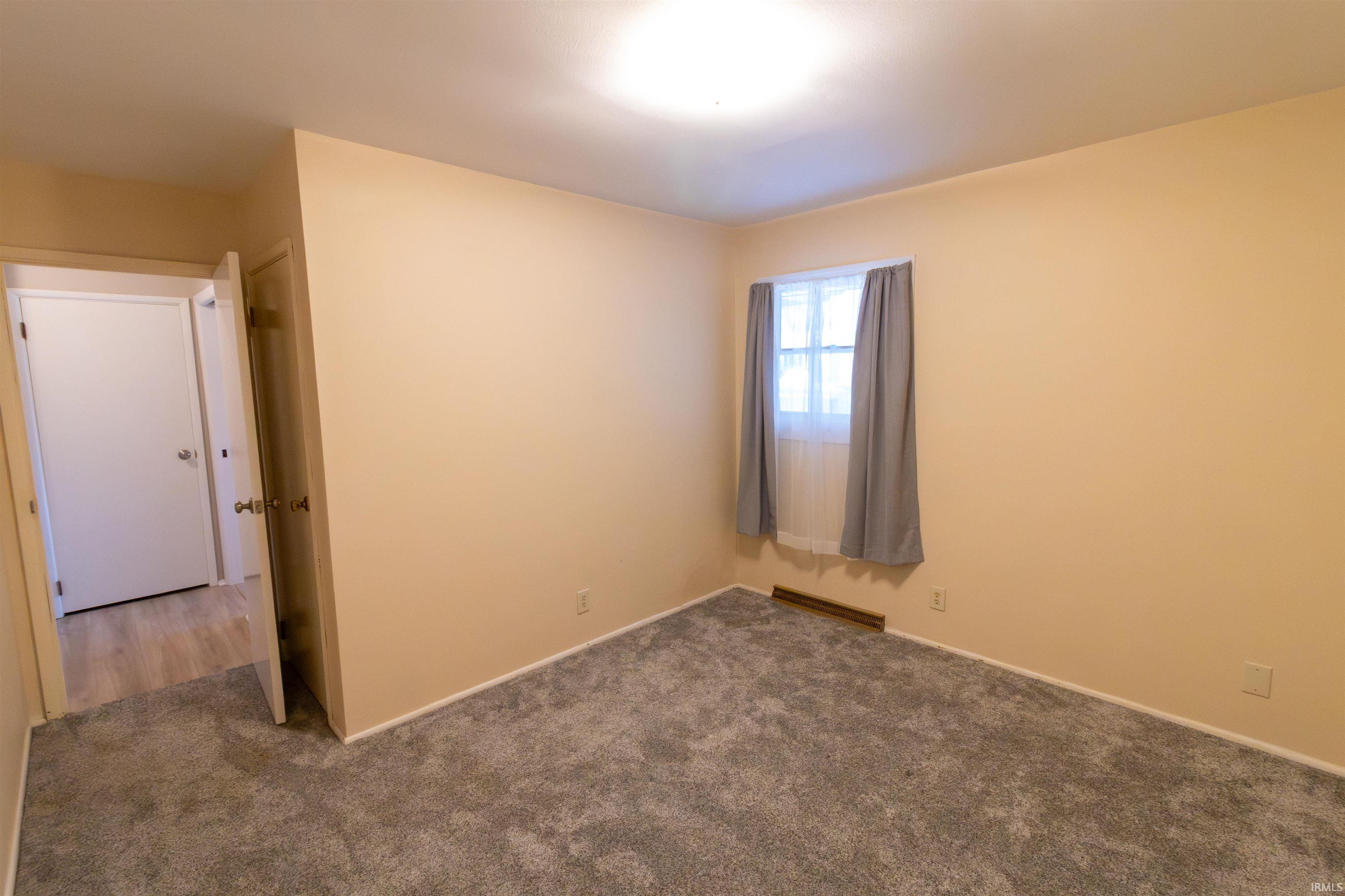Unfurnished room with carpet flooring and baseboard heating