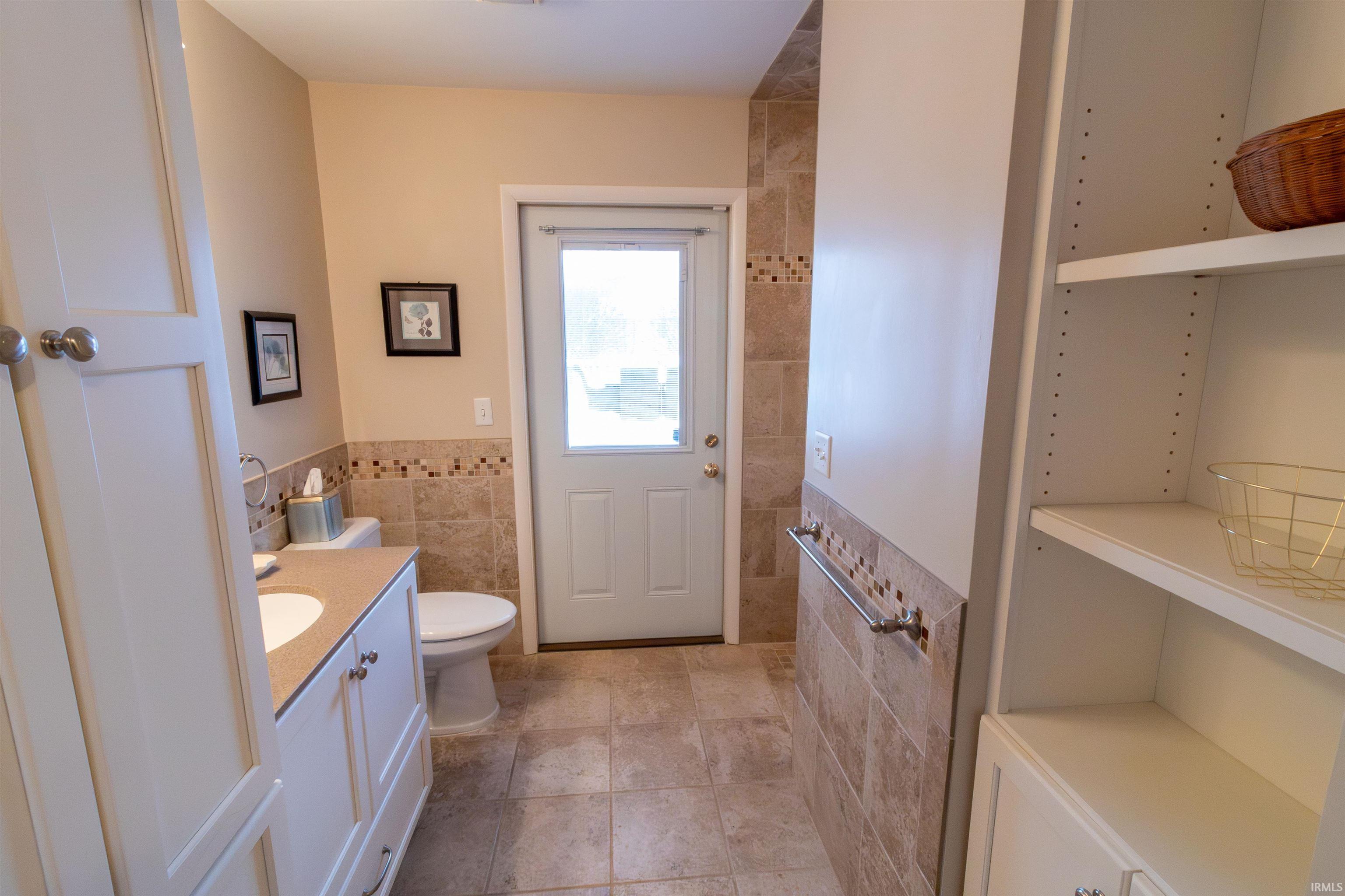 Bathroom with tile walls, vanity, a wainscoted wall, and light tile patterned floors