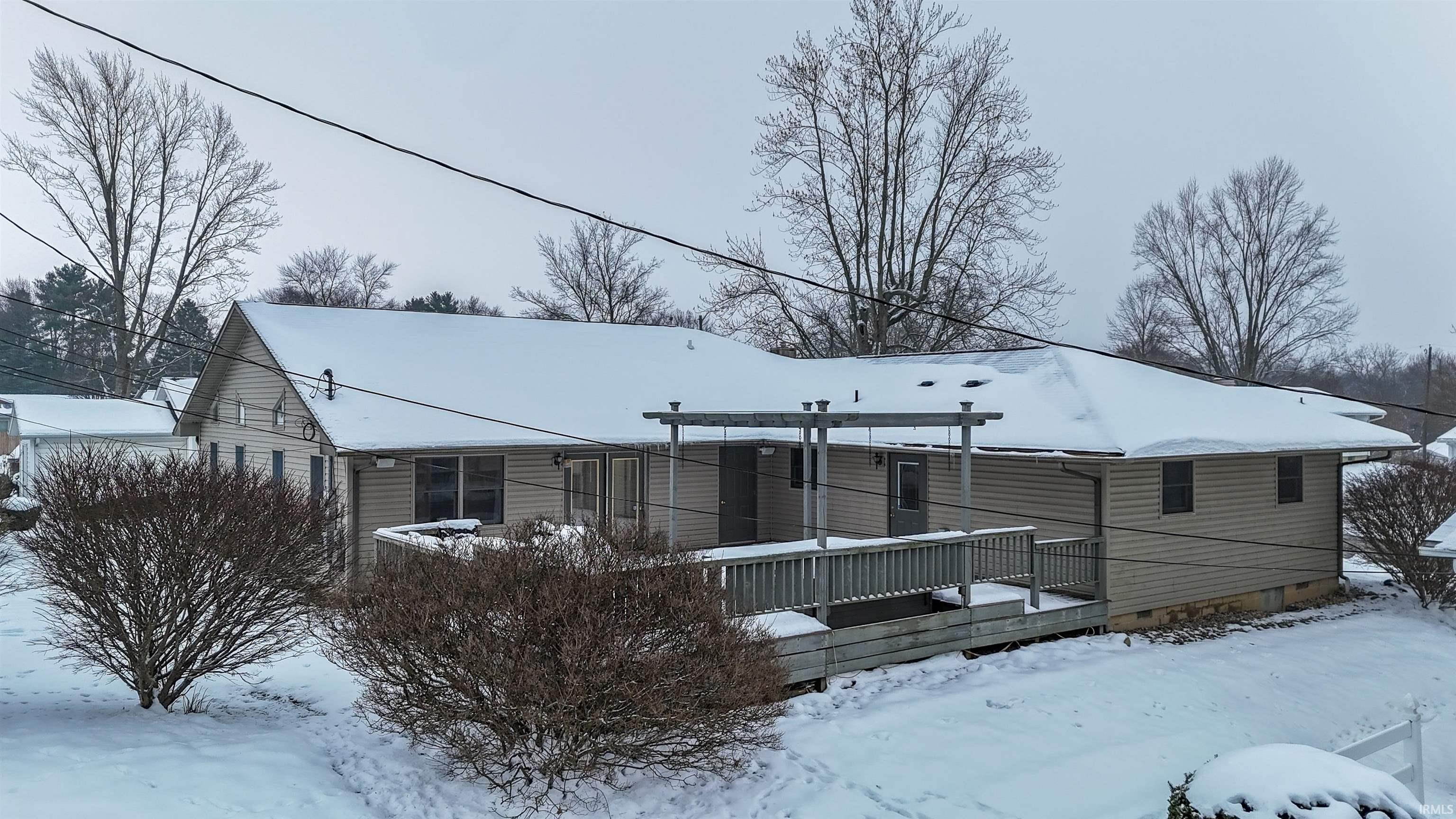 Snow covered rear of property with a deck