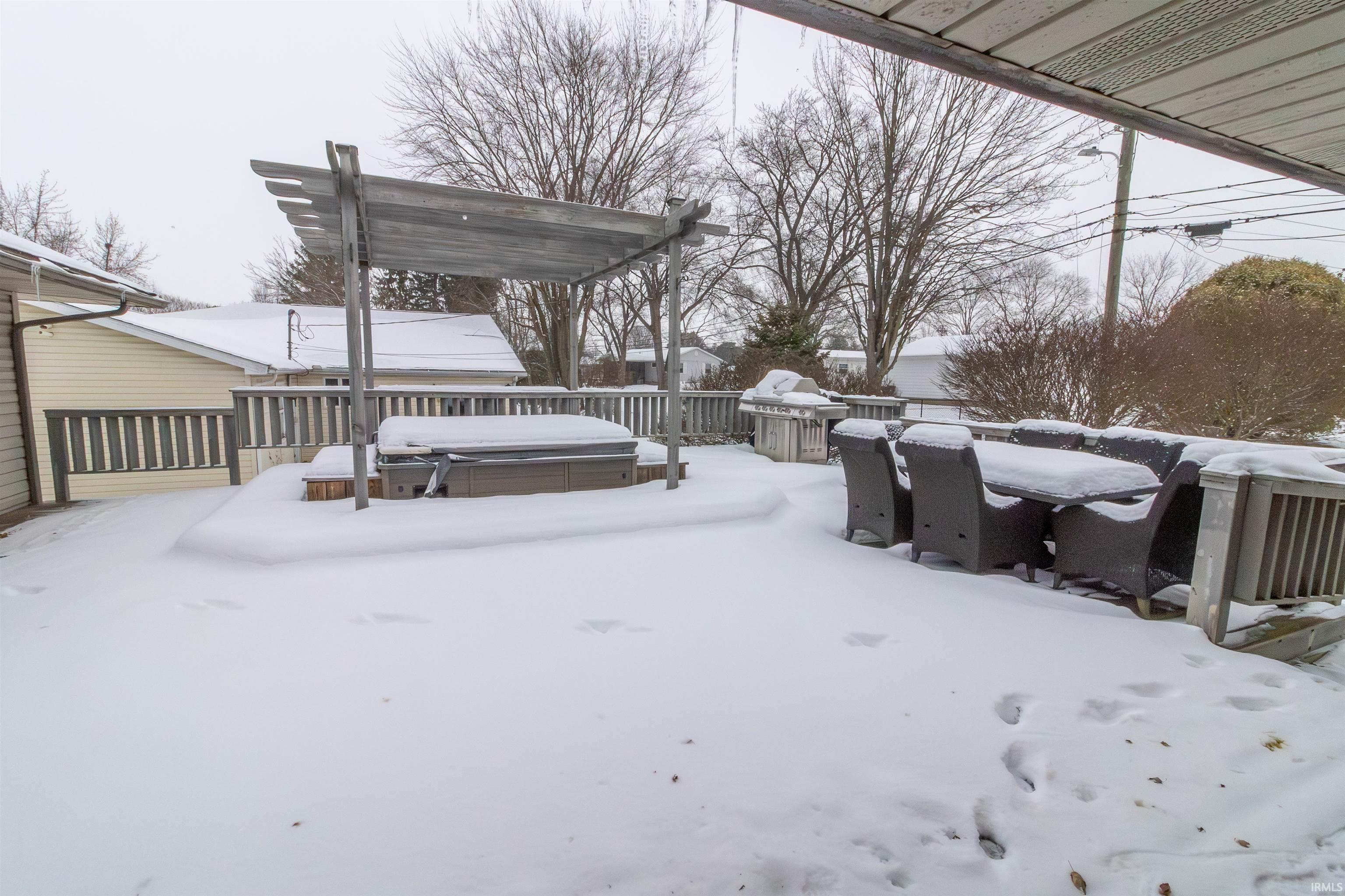 Yard covered in snow featuring a deck and a hot tub