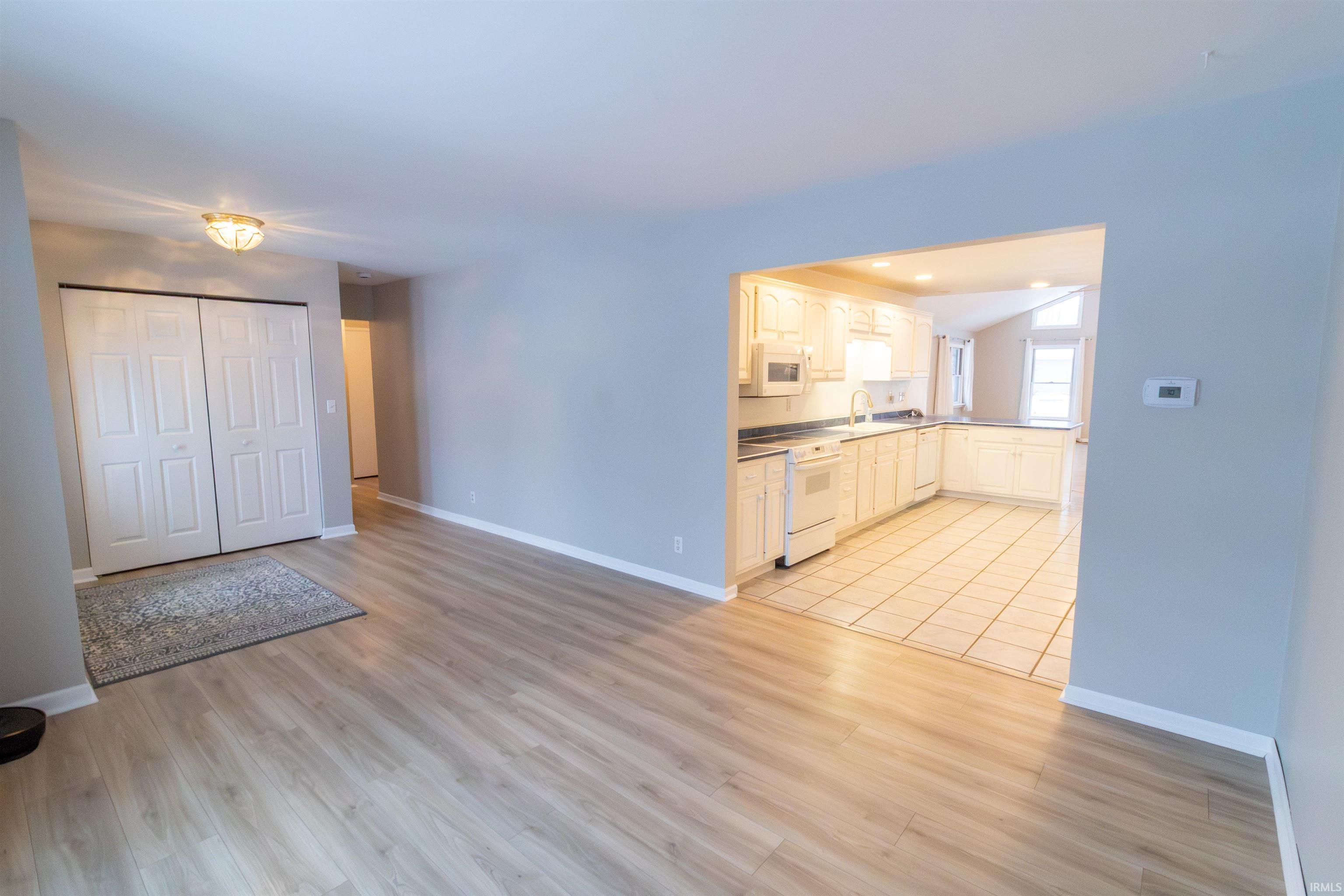 Kitchen featuring white appliances, white cabinetry, light wood finished floors, and open floor plan
