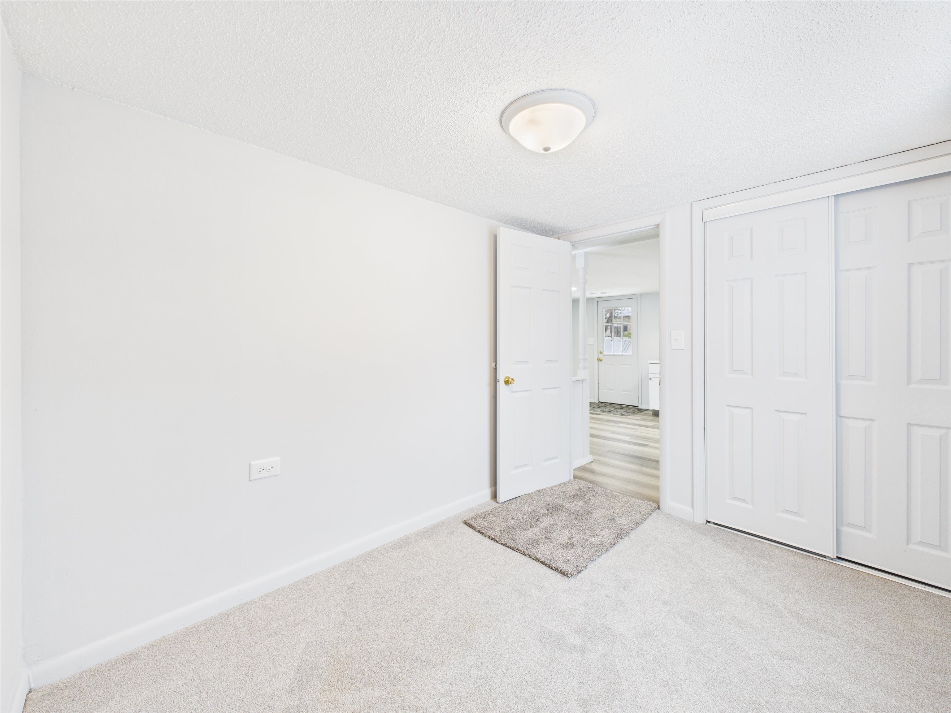 Unfurnished bedroom with a textured ceiling, carpet flooring, and a closet