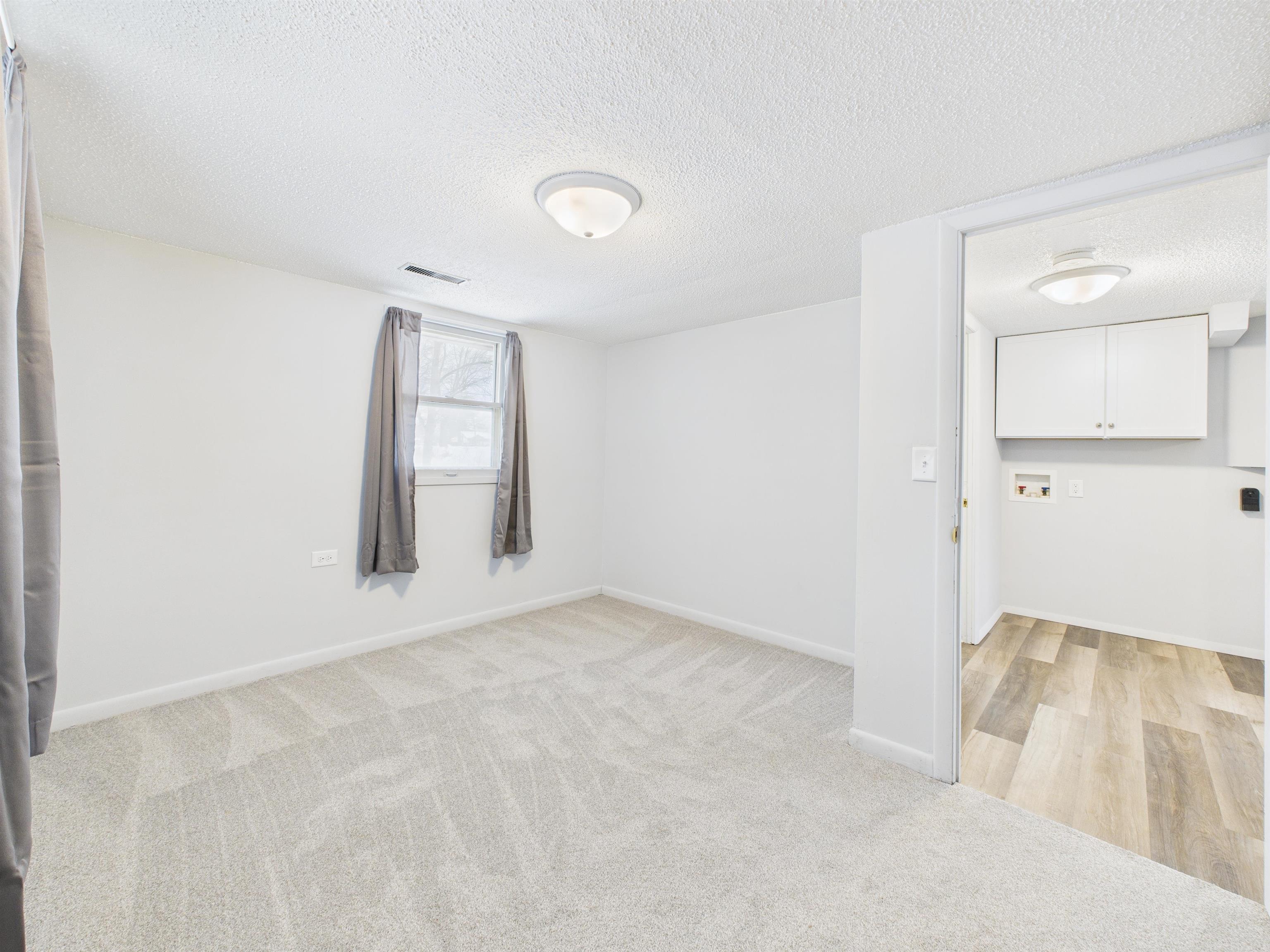 Unfurnished room featuring a textured ceiling and light carpet