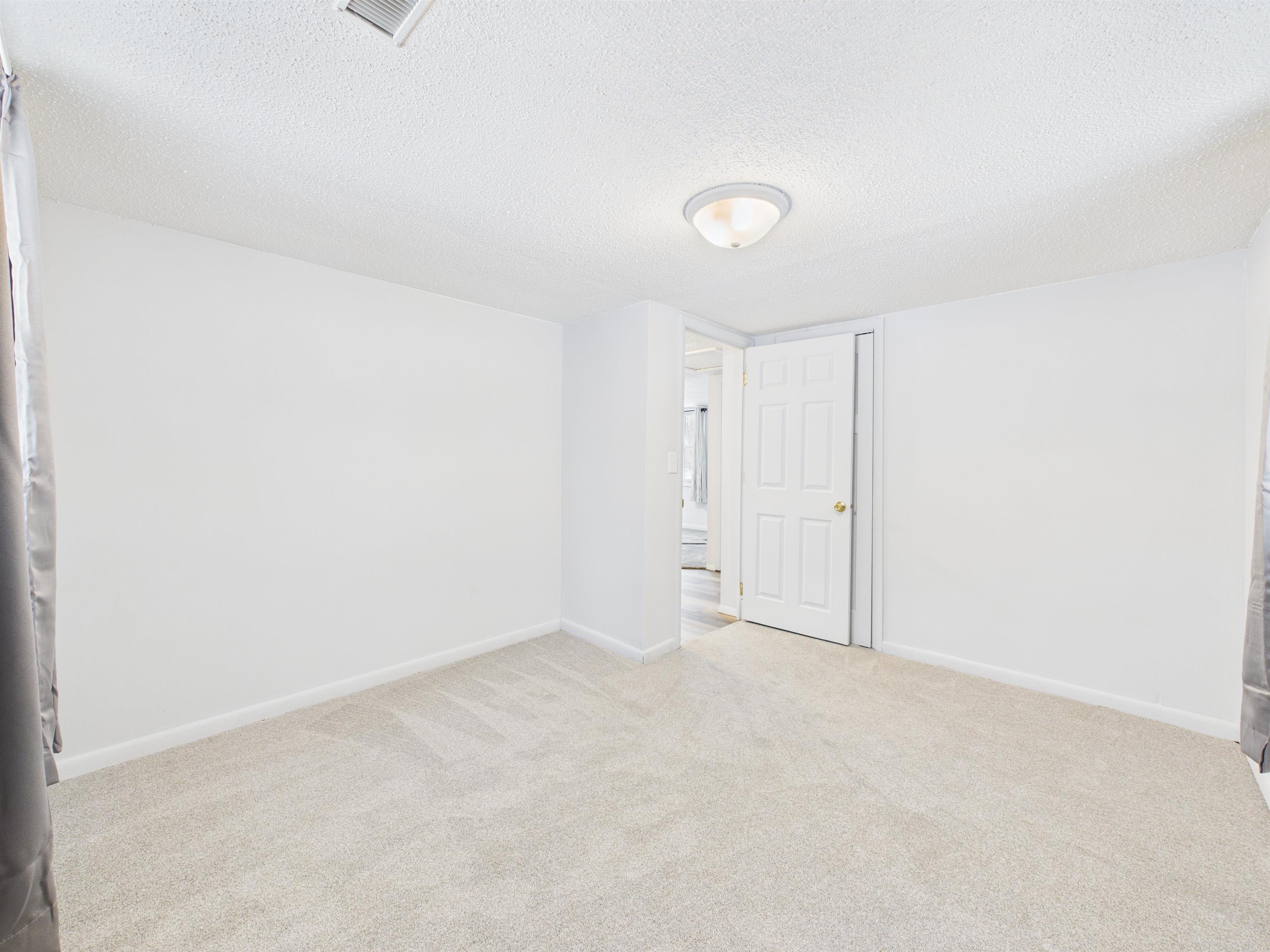 Empty room with a textured ceiling and light carpet