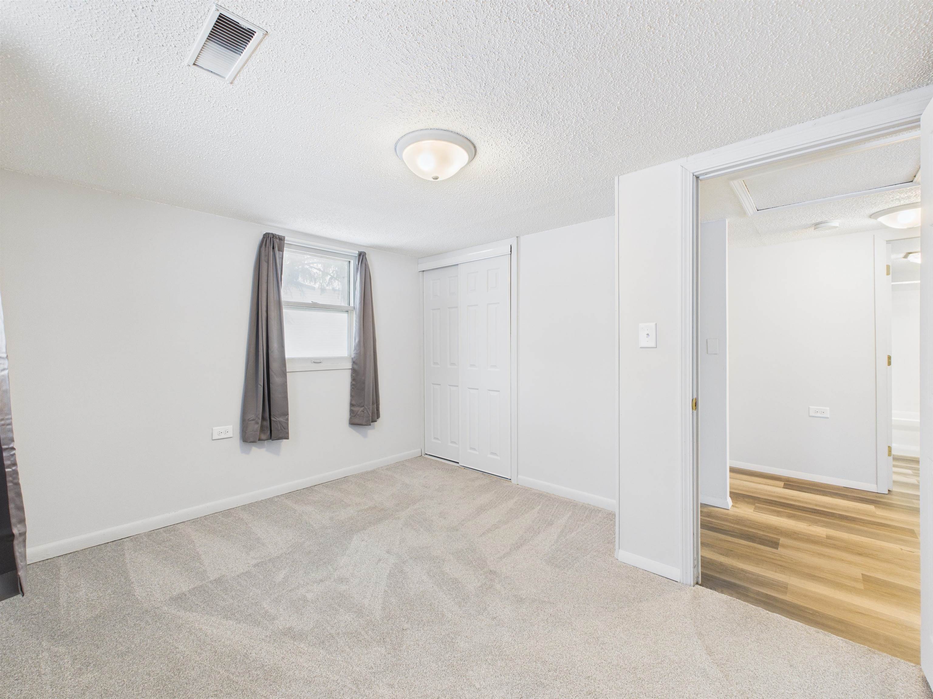 Unfurnished bedroom featuring a textured ceiling, light colored carpet, and a closet