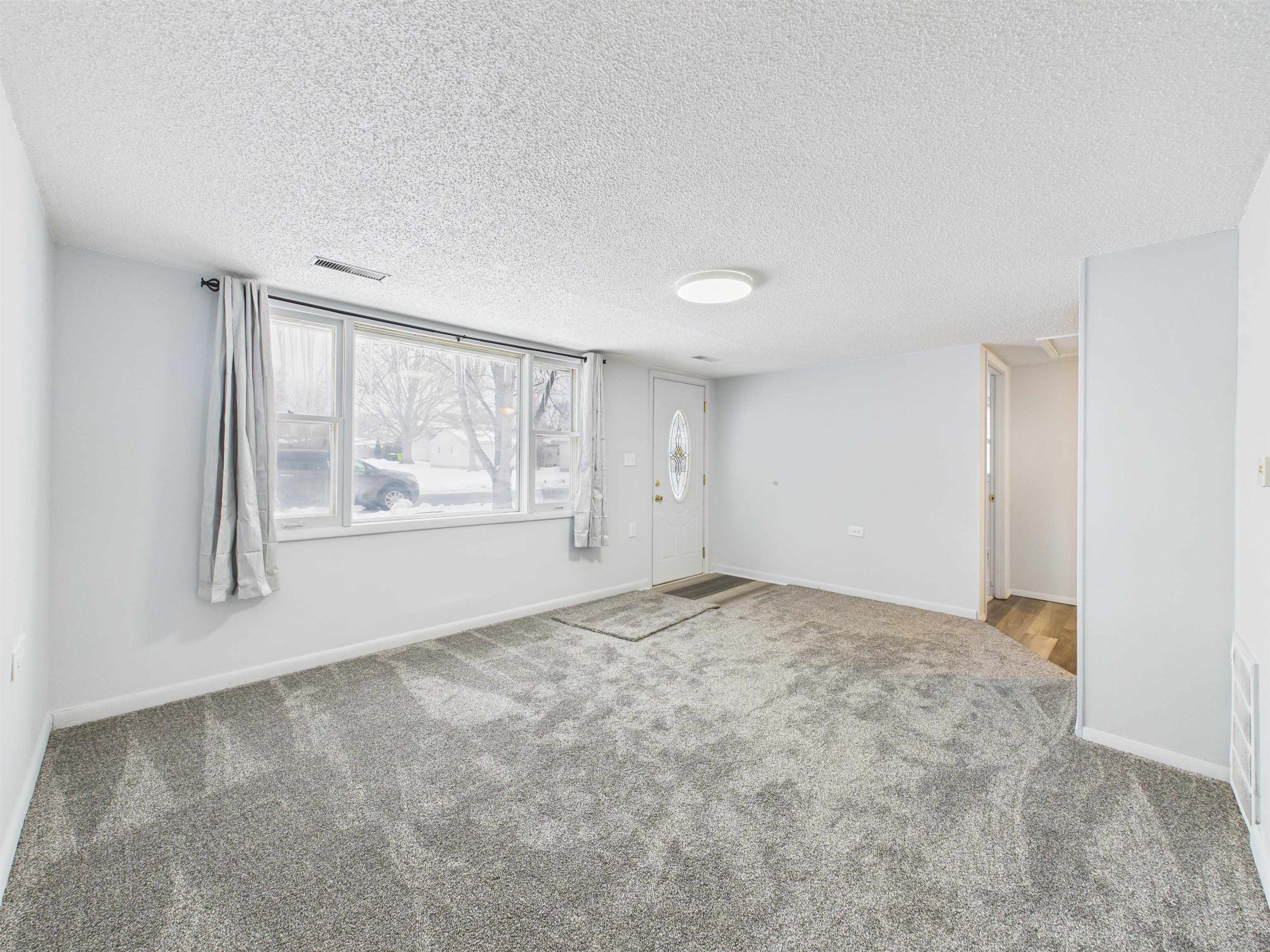 Empty room with a textured ceiling and carpet