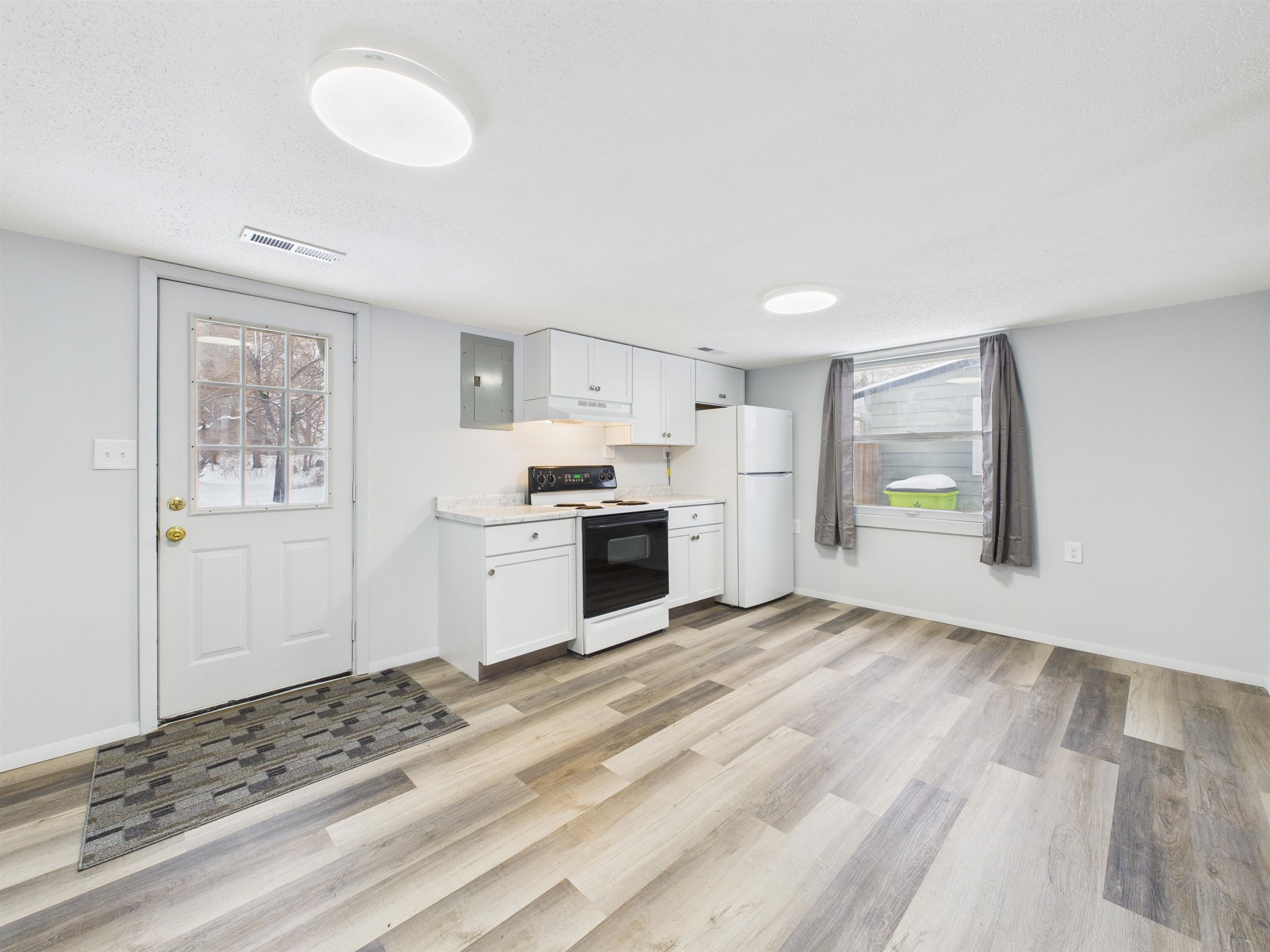 Kitchen with light countertops, electric range, white cabinetry, freestanding refrigerator, and electric panel