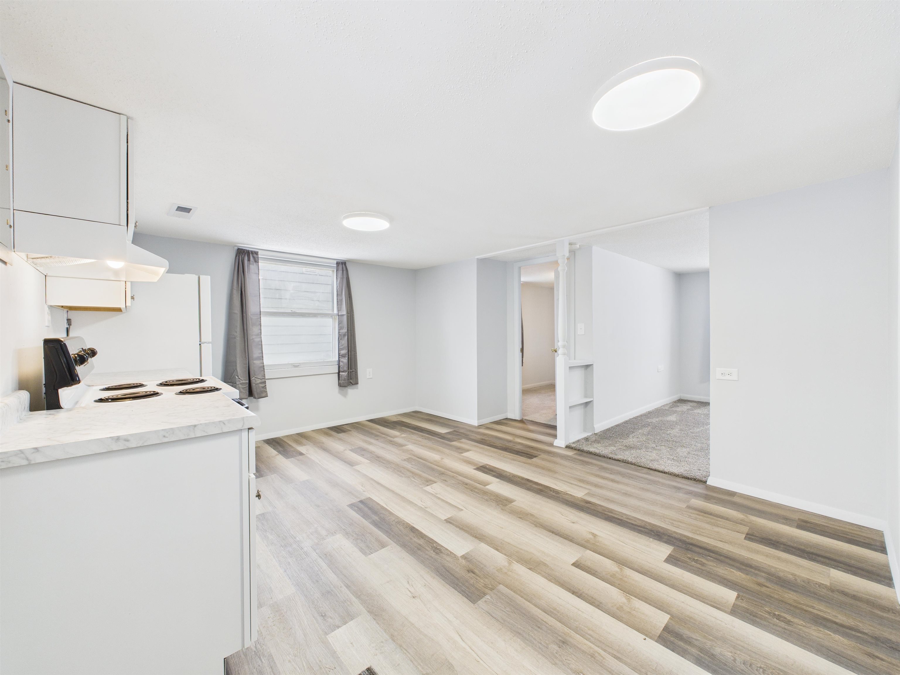 Kitchen with light countertops, white cabinets, light wood-style floors, and electric range
