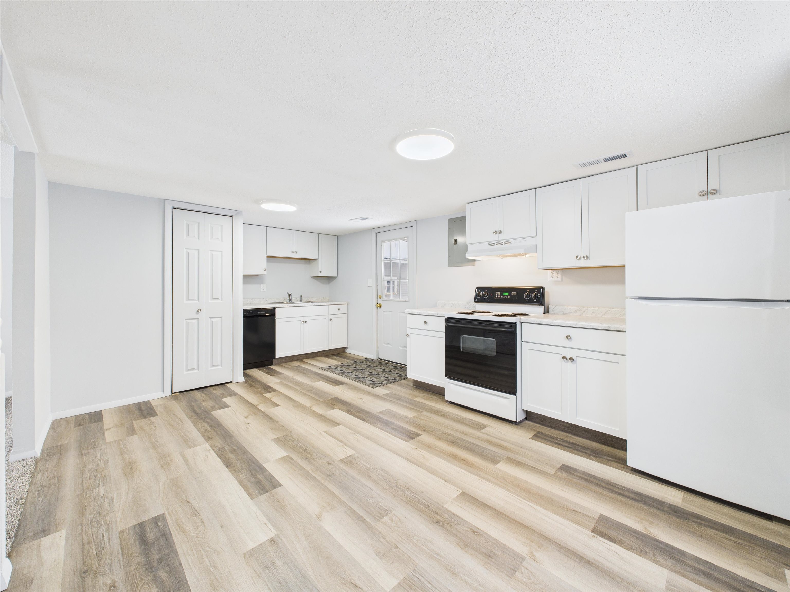 Kitchen featuring freestanding refrigerator, range with electric stovetop, light countertops, white cabinets, and light wood-style floors