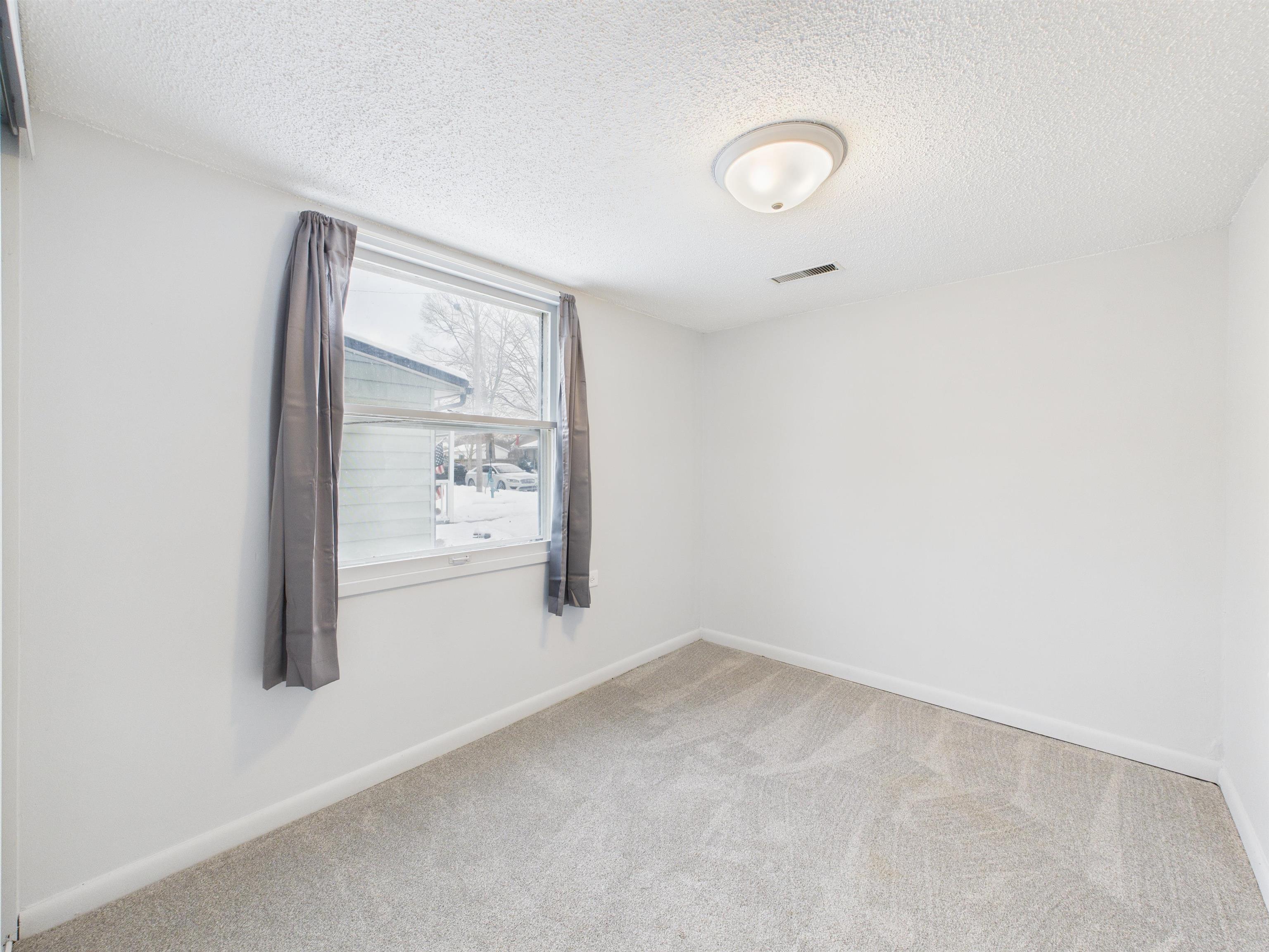 Empty room with a textured ceiling and carpet floors