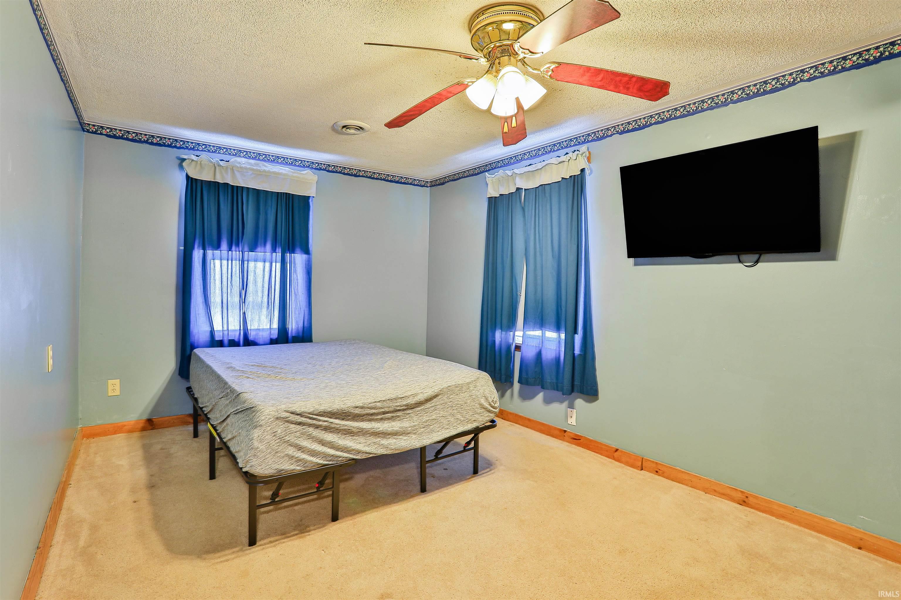 Carpeted bedroom with a textured ceiling and ceiling fan