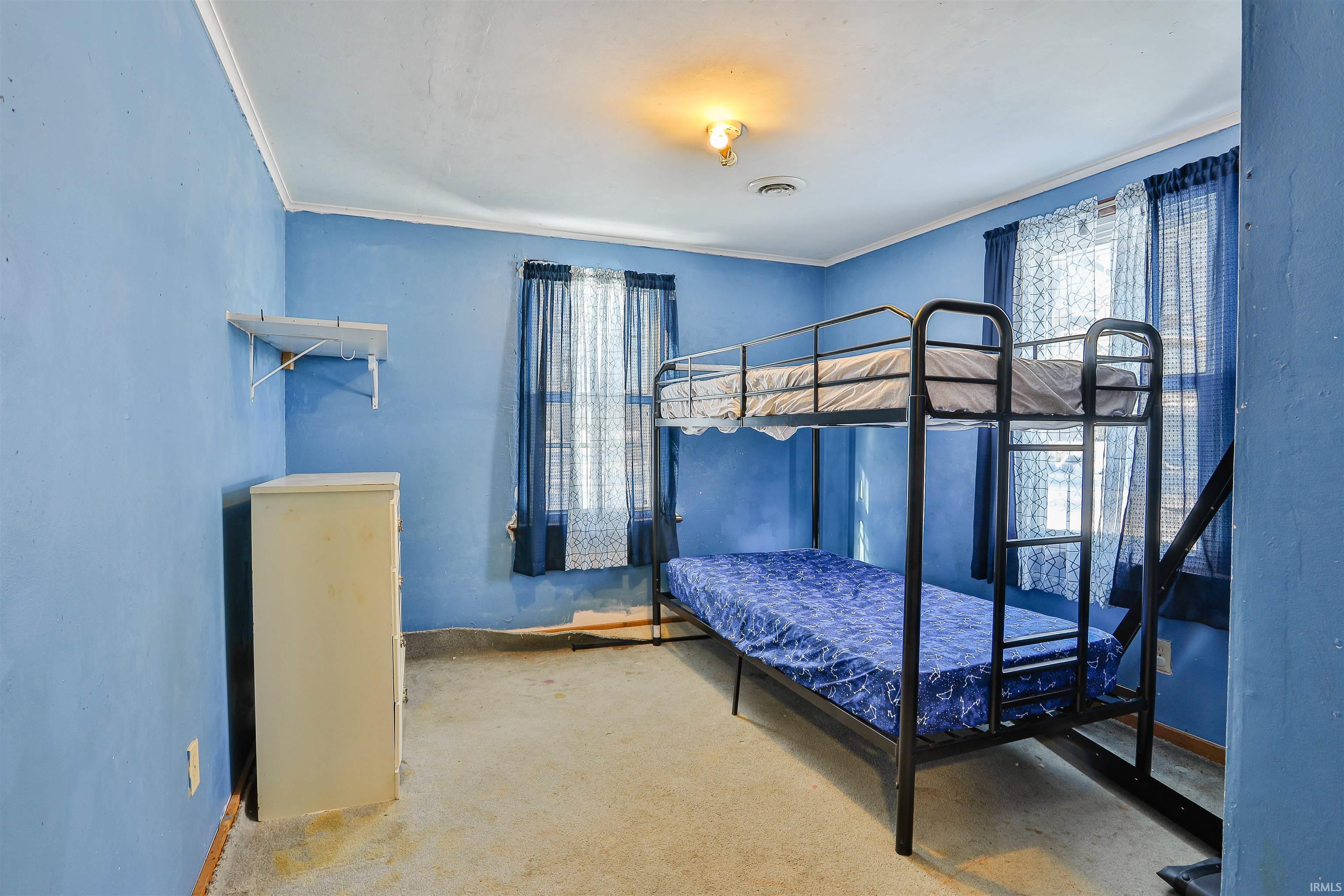 Carpeted bedroom featuring crown molding