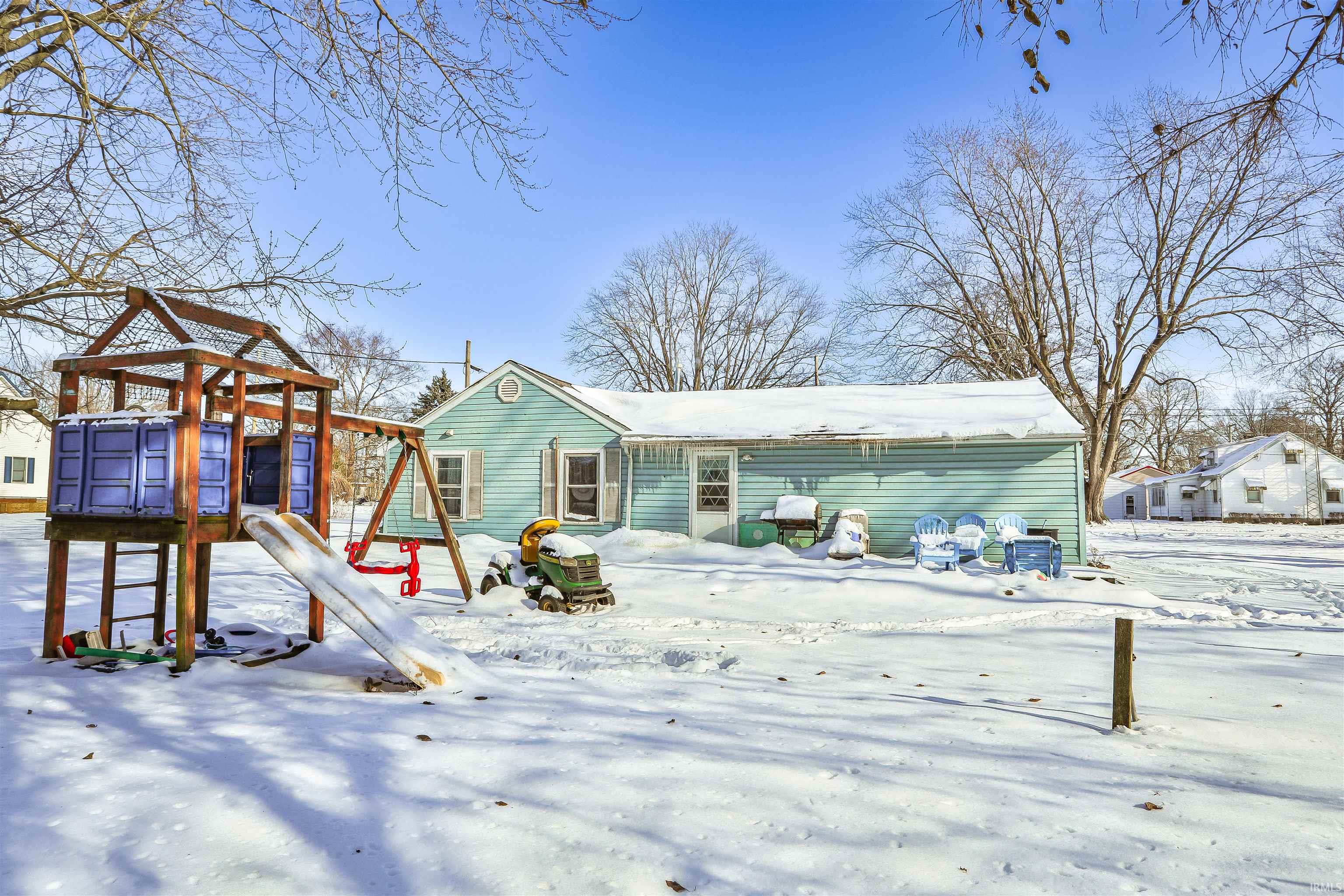 Snow covered back of property with a playground