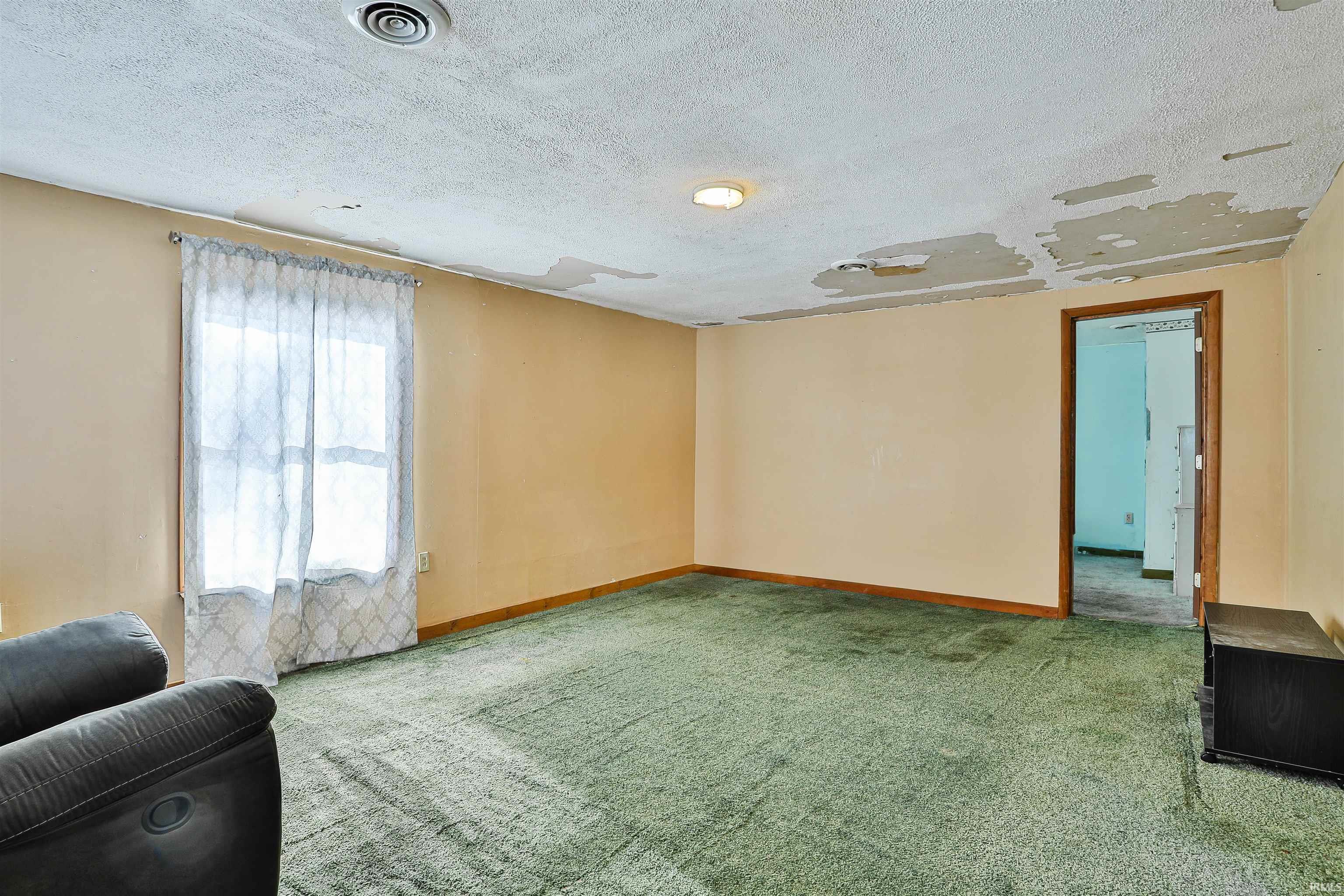 Unfurnished living room featuring a textured ceiling and carpet