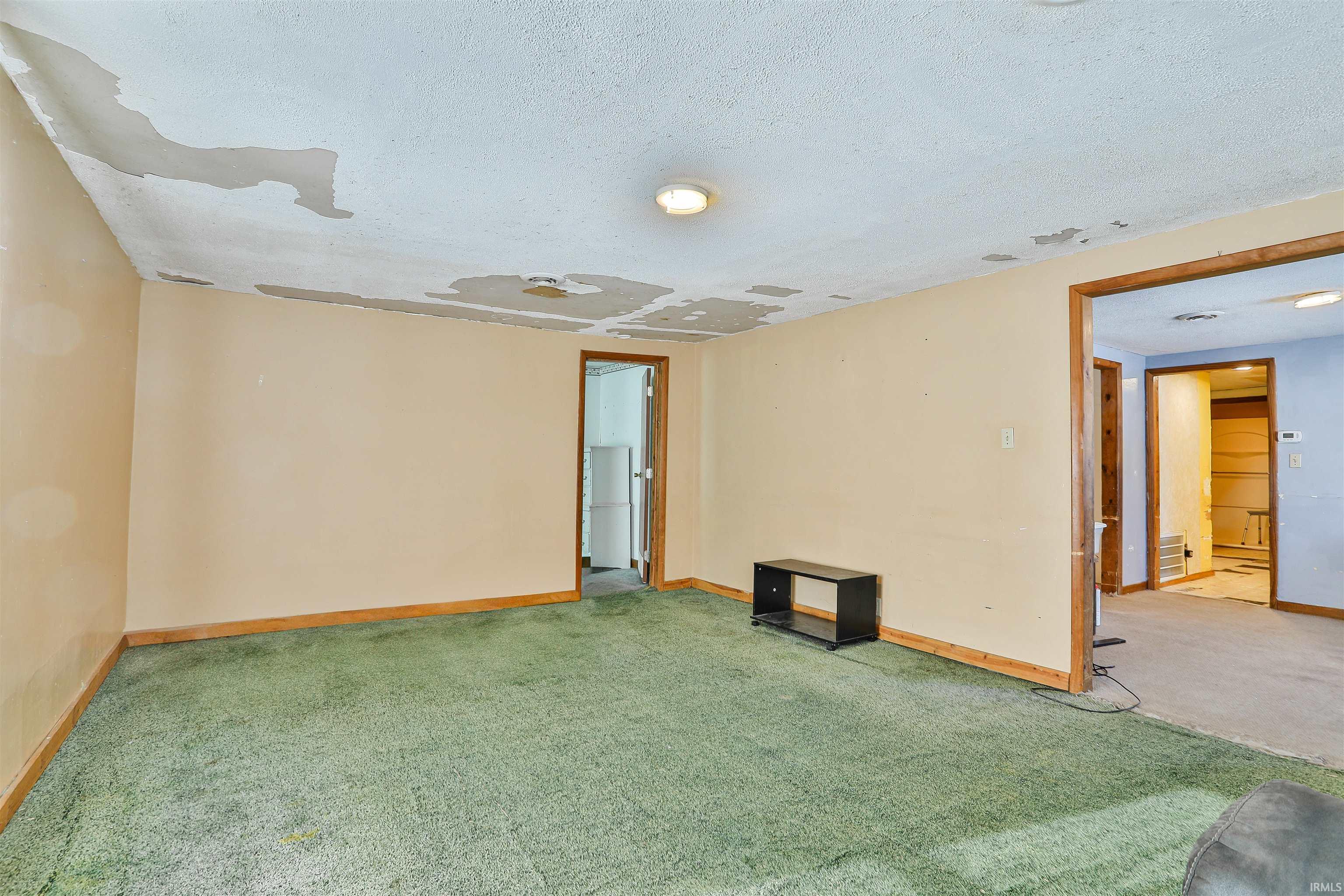 Carpeted spare room with a textured ceiling and baseboards