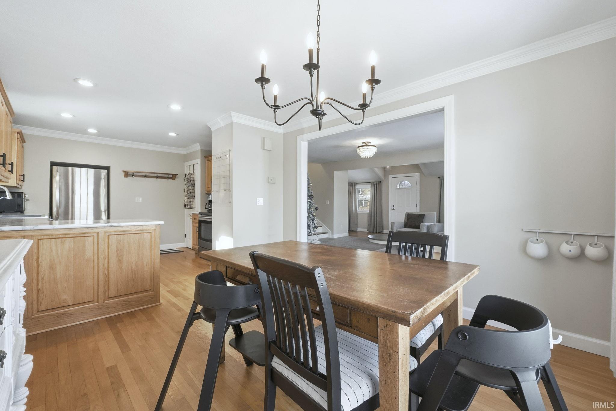 Dining room with ornamental molding, light wood-type flooring, and a chandelier