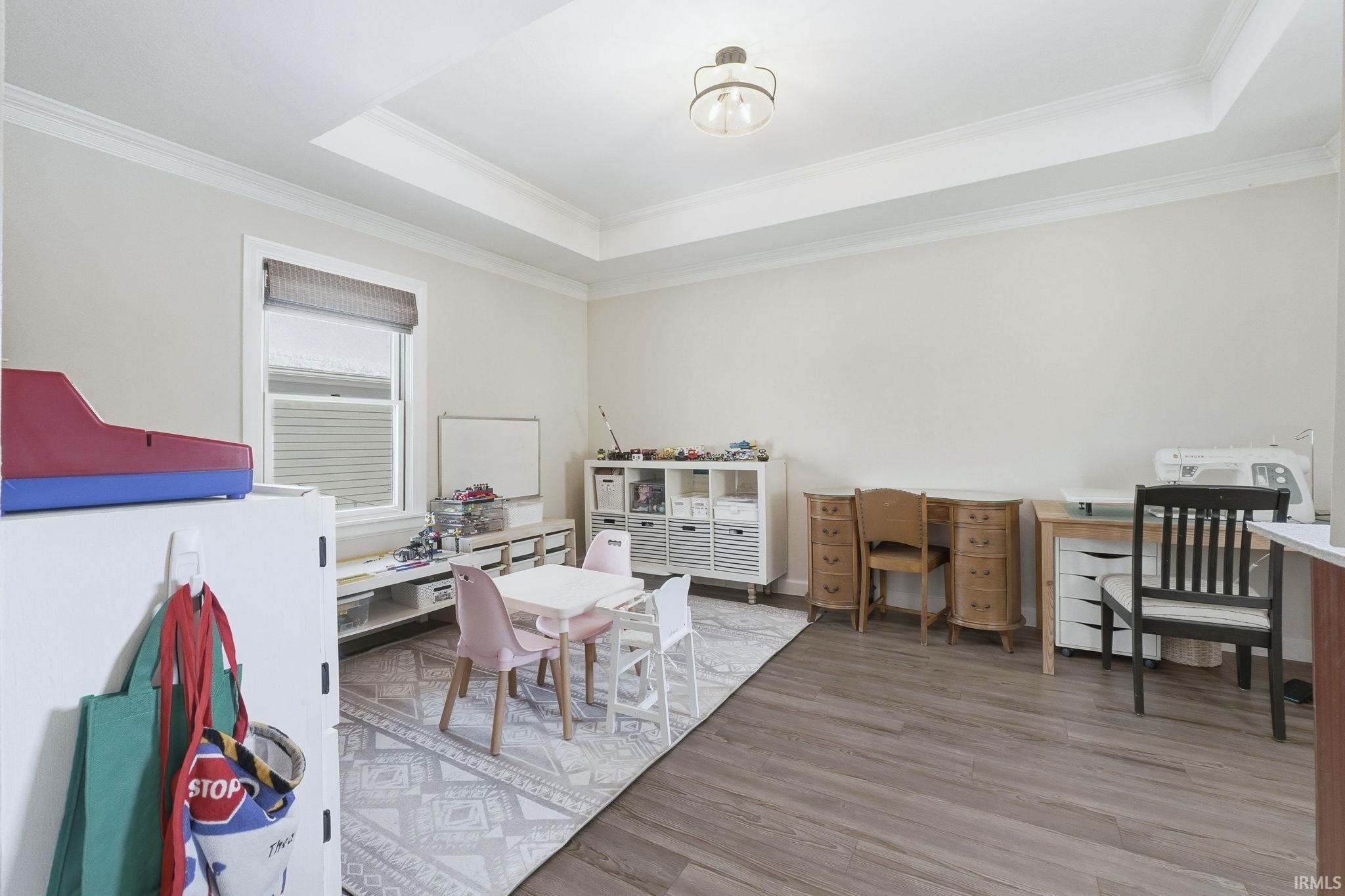 Recreation room with a desk, light wood-style flooring, a tray ceiling, and crown molding