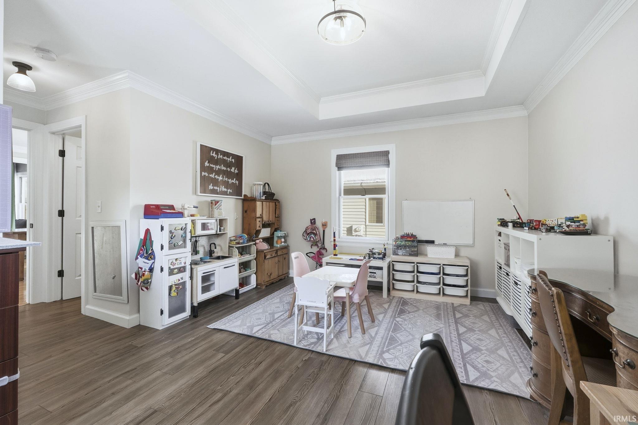 Office space featuring dark wood-style floors, crown molding, and a tray ceiling