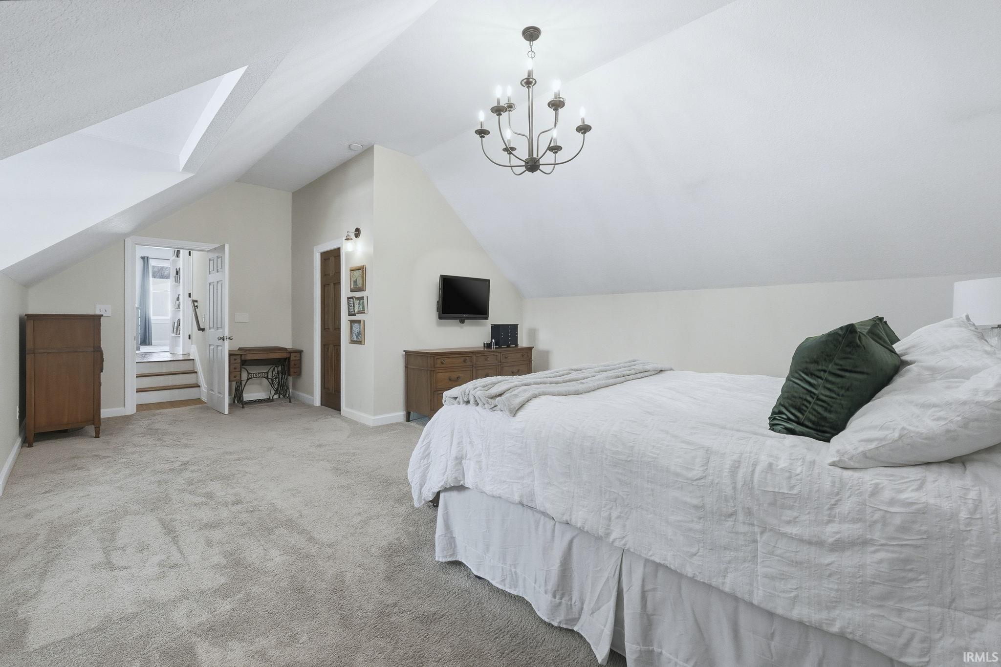 Carpeted bedroom with vaulted ceiling and a chandelier