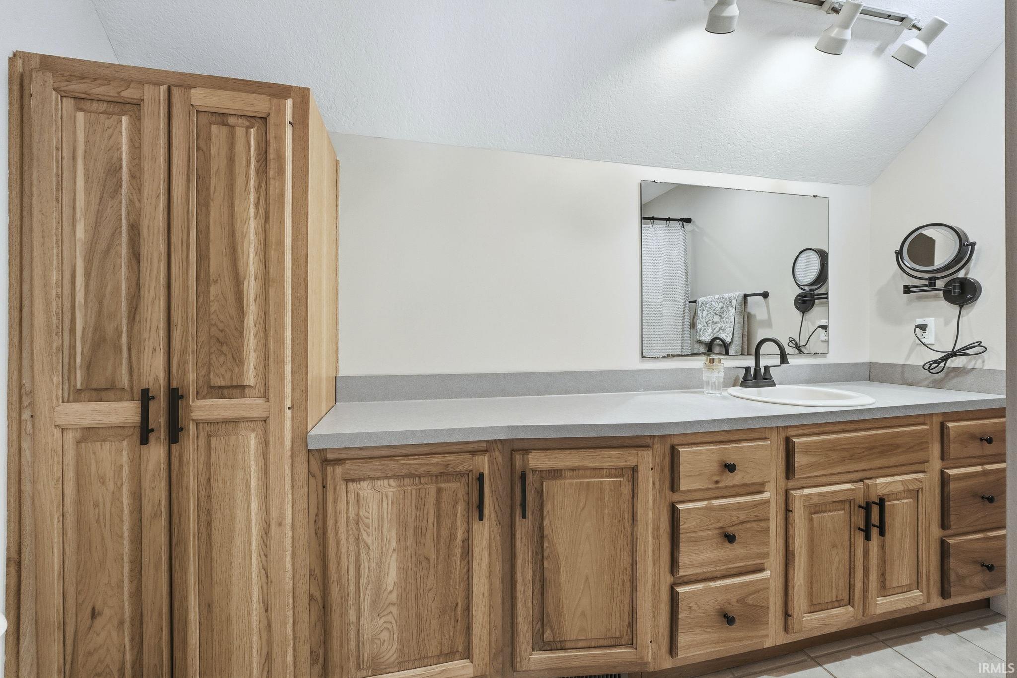 Bathroom with vanity, light tile patterned floors, and a textured ceiling