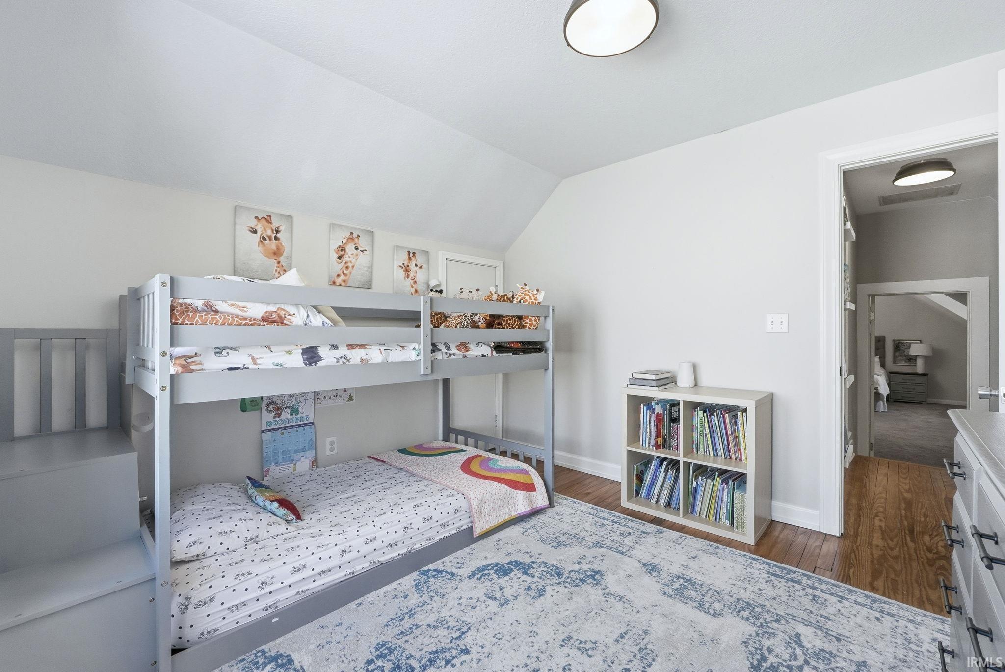 Bedroom with dark wood finished floors and vaulted ceiling