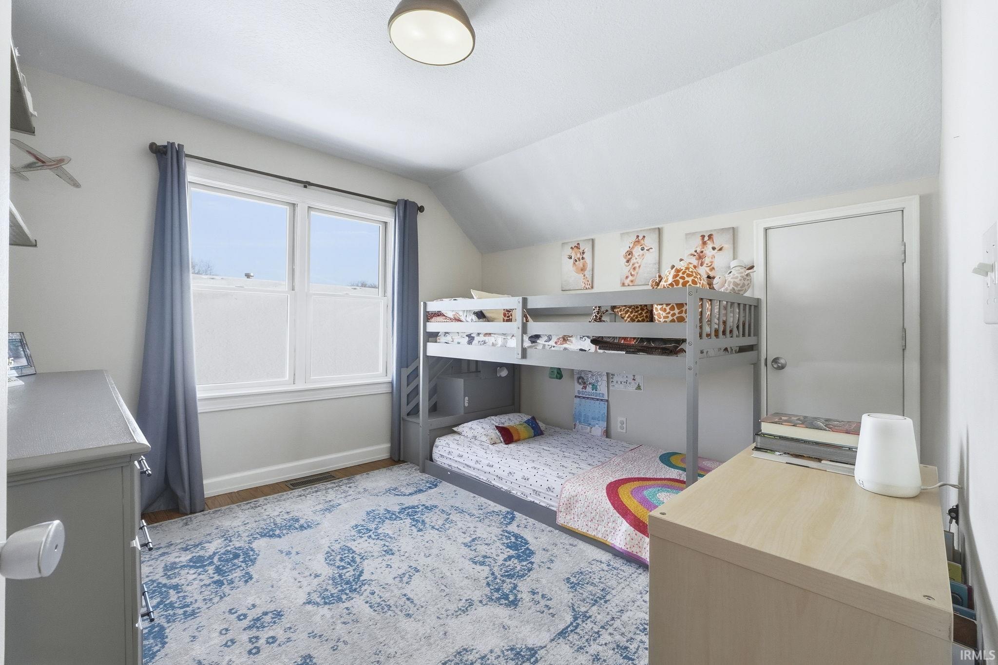 Bedroom with lofted ceiling and wood finished floors