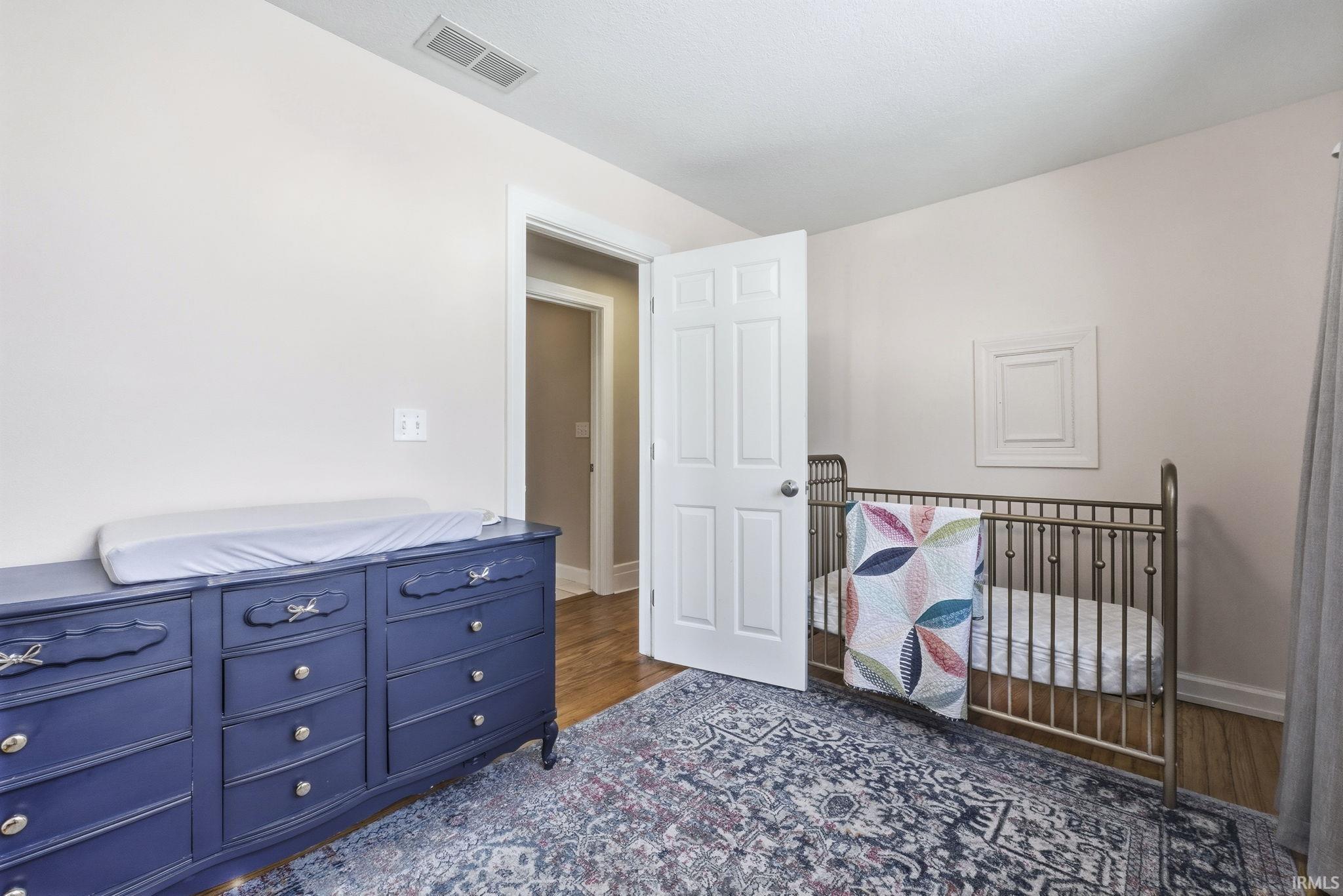Bedroom with a crib and dark wood finished floors