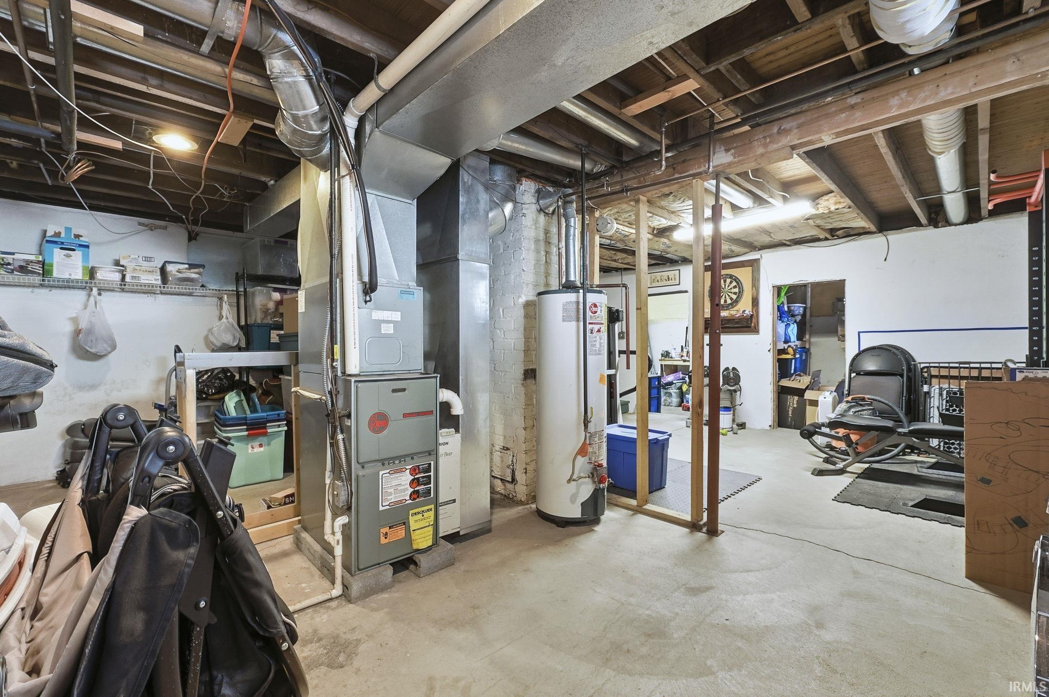 Unfinished below grade area featuring water heater and heating unit